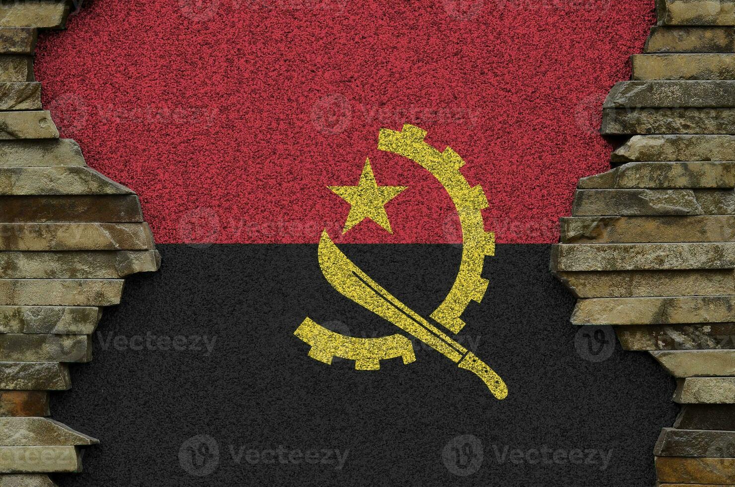 Angola flag depicted in paint colors on old stone wall closeup. Textured banner on rock wall background photo