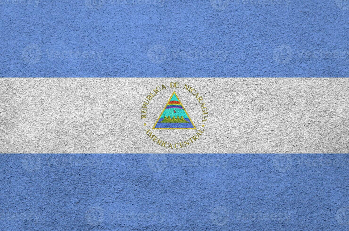 Nicaragua flag depicted in bright paint colors on old relief plastering wall. Textured banner on rough background photo