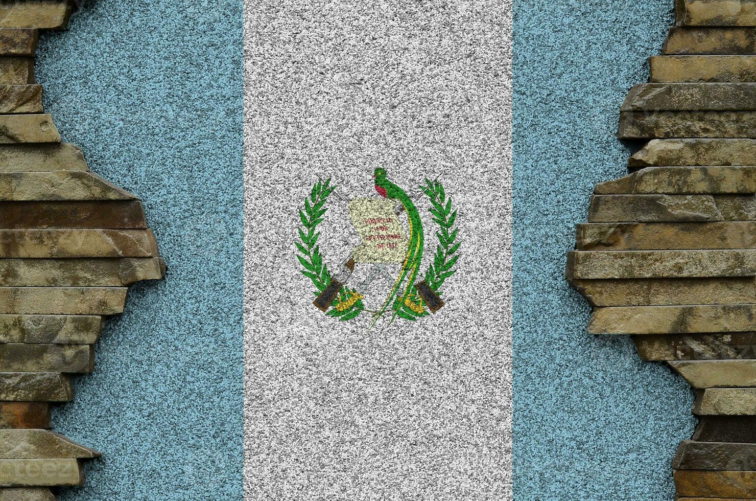 Guatemala flag depicted in paint colors on old stone wall closeup. Textured banner on rock wall background photo