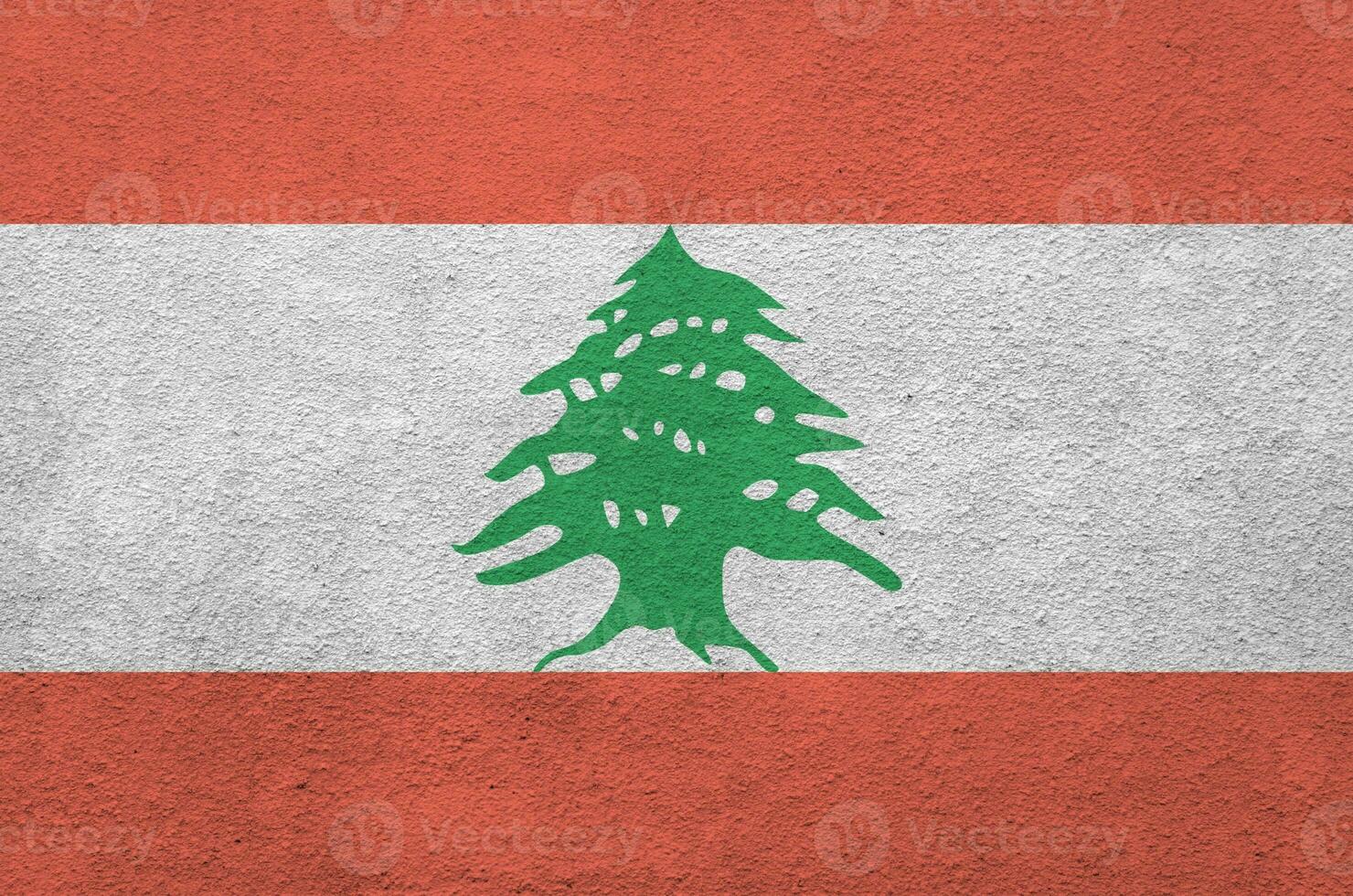 Lebanon flag depicted in bright paint colors on old relief plastering wall. Textured banner on rough background photo