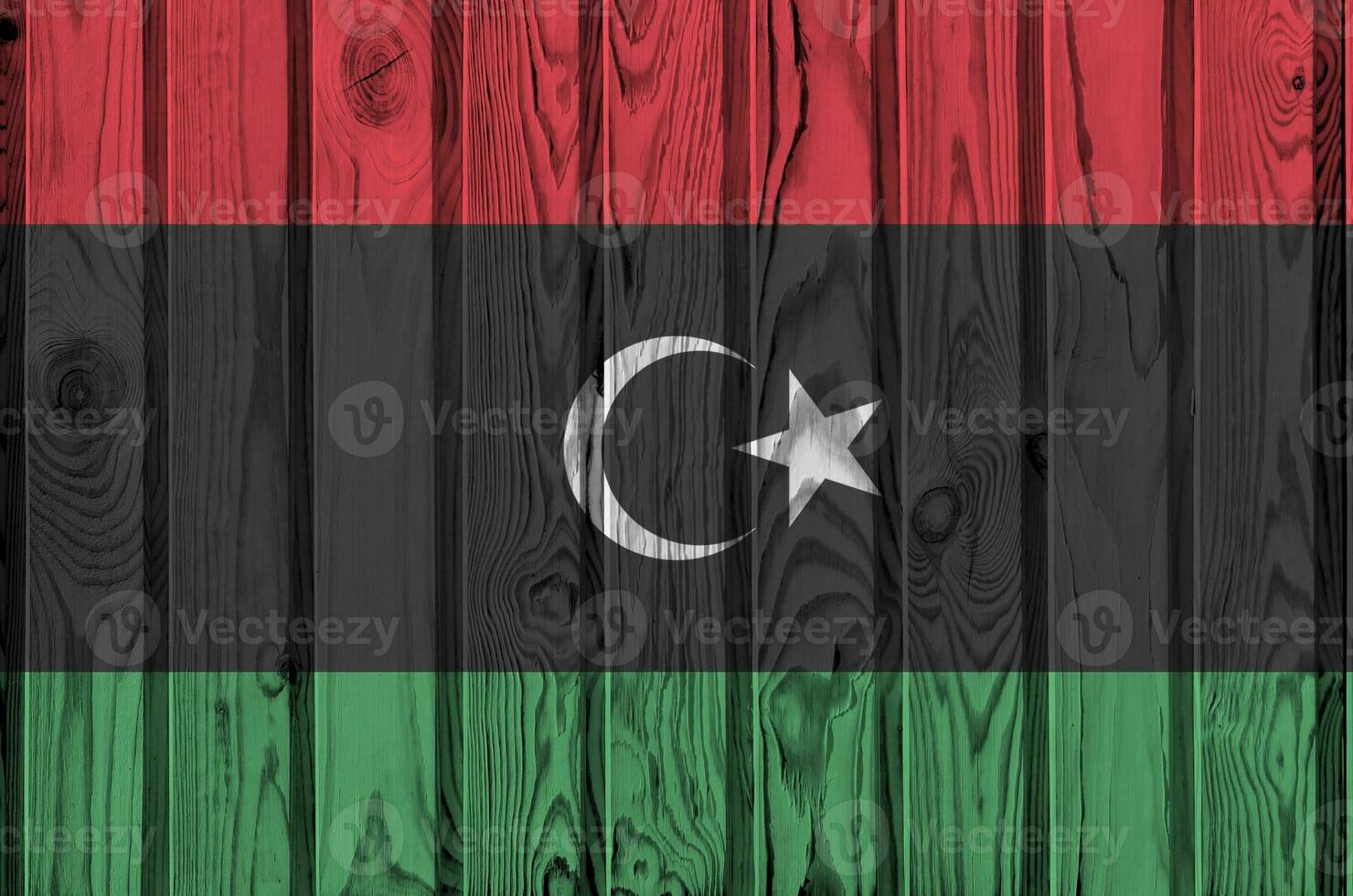 Libya flag depicted in bright paint colors on old wooden wall. Textured banner on rough background photo