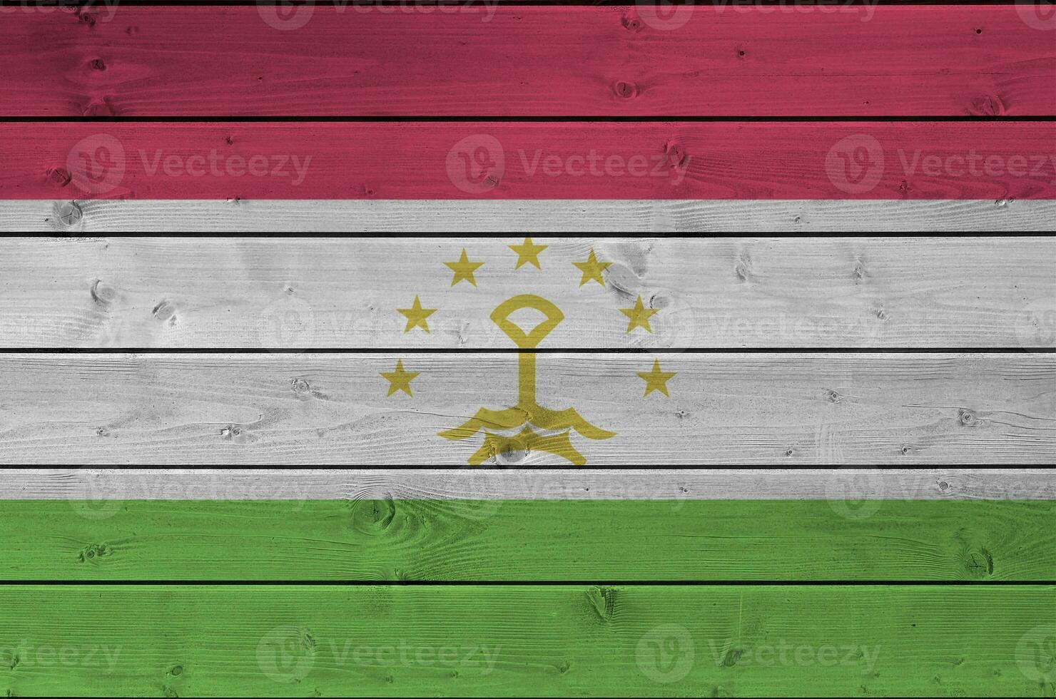 Tajikistan flag depicted in bright paint colors on old wooden wall. Textured banner on rough background photo