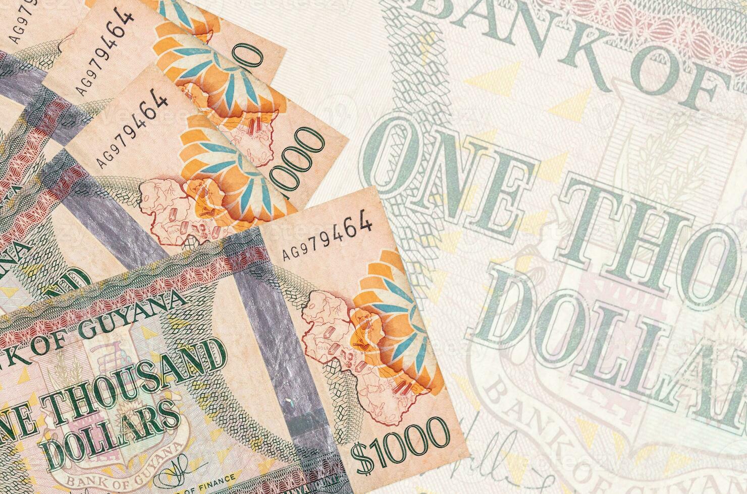 1000 Guyanese dollars bills lies in stack on background of big semi-transparent banknote. Abstract business background photo