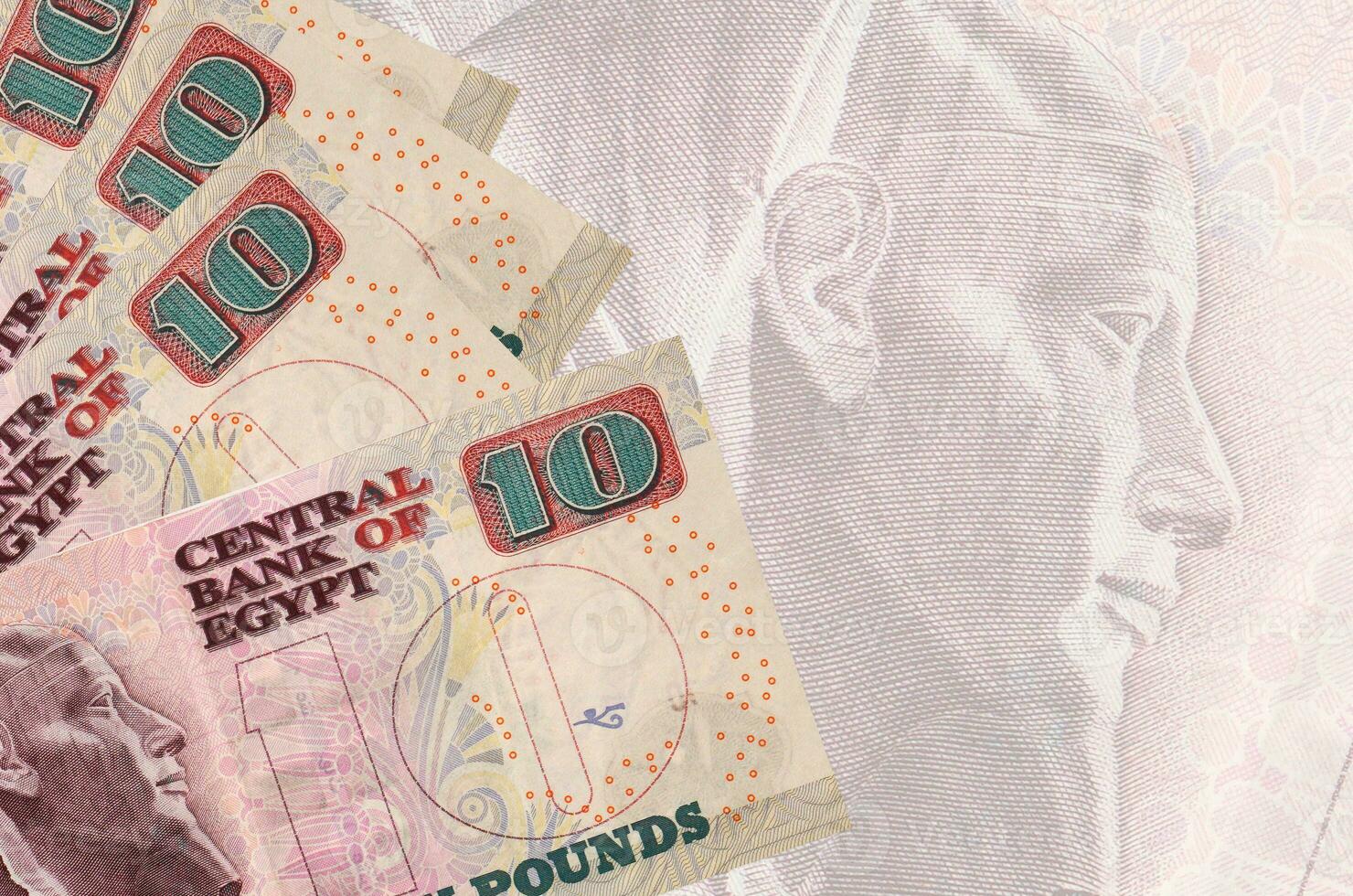 10 Egyptian pounds bills lies in stack on background of big semi-transparent banknote. Abstract business background photo