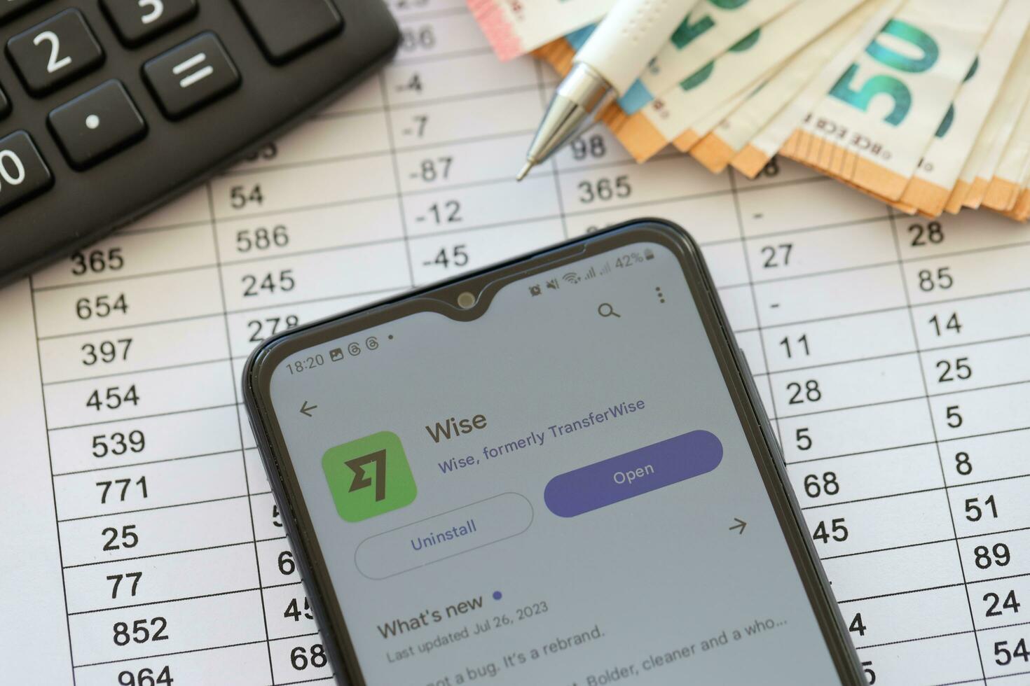 TERNOPIL, UKRAINE - AUGUST 3, 2023 Wise application on screen on modern smartphone and many bills of euro currency photo