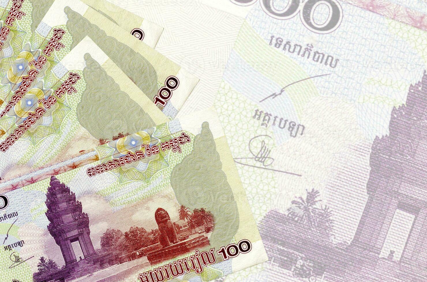 100 Cambodian riels bills lies in stack on background of big semi-transparent banknote. Abstract business background photo