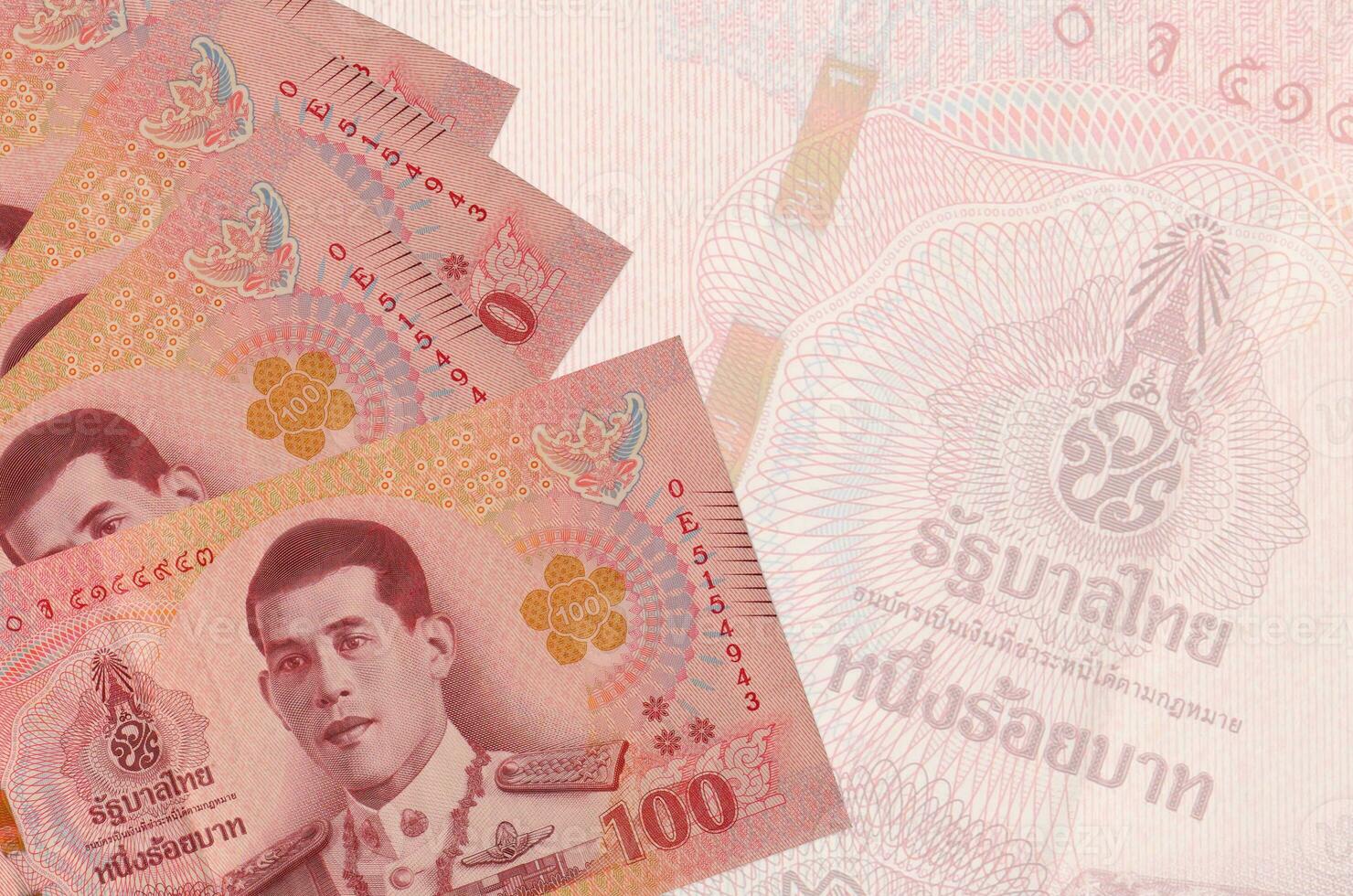 100 Thai baht bills lies in stack on background of big semi-transparent banknote. Abstract business background photo