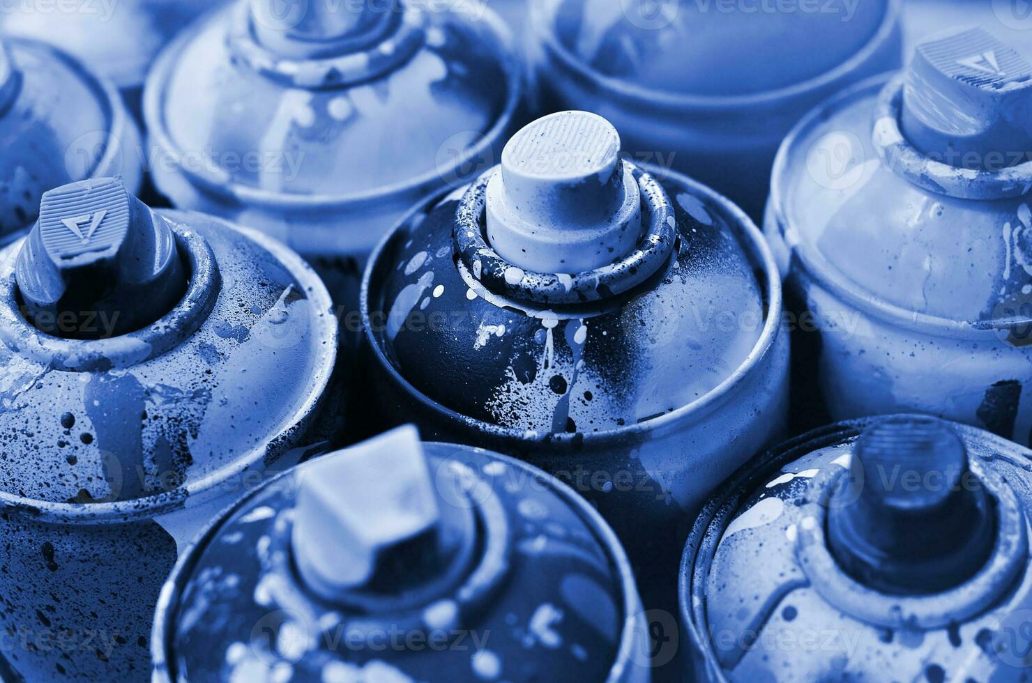 A lot of used spray cans of paint close-up. Dirty and smeared cans for drawing graffiti. The concept of a sweeping and careless drawing of paint. phantom classic blue color photo