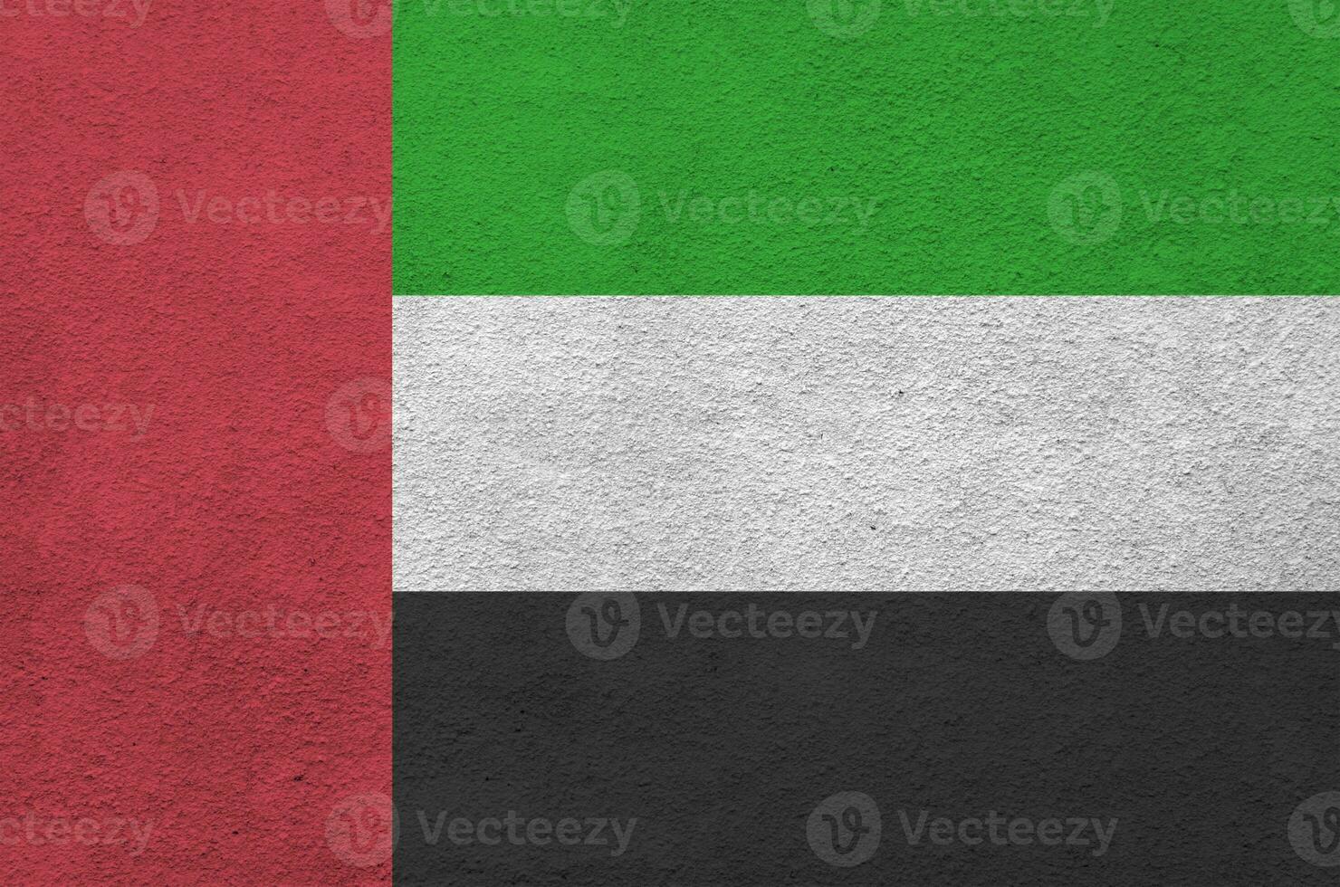 United Arab Emirates flag depicted in bright paint colors on old relief plastering wall. Textured banner on rough background photo