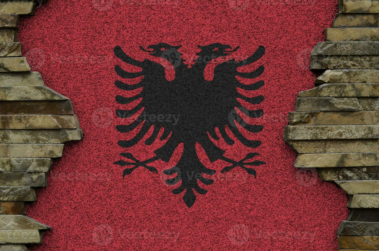 Albania flag depicted in paint colors on old stone wall closeup. Textured banner on rock wall background photo