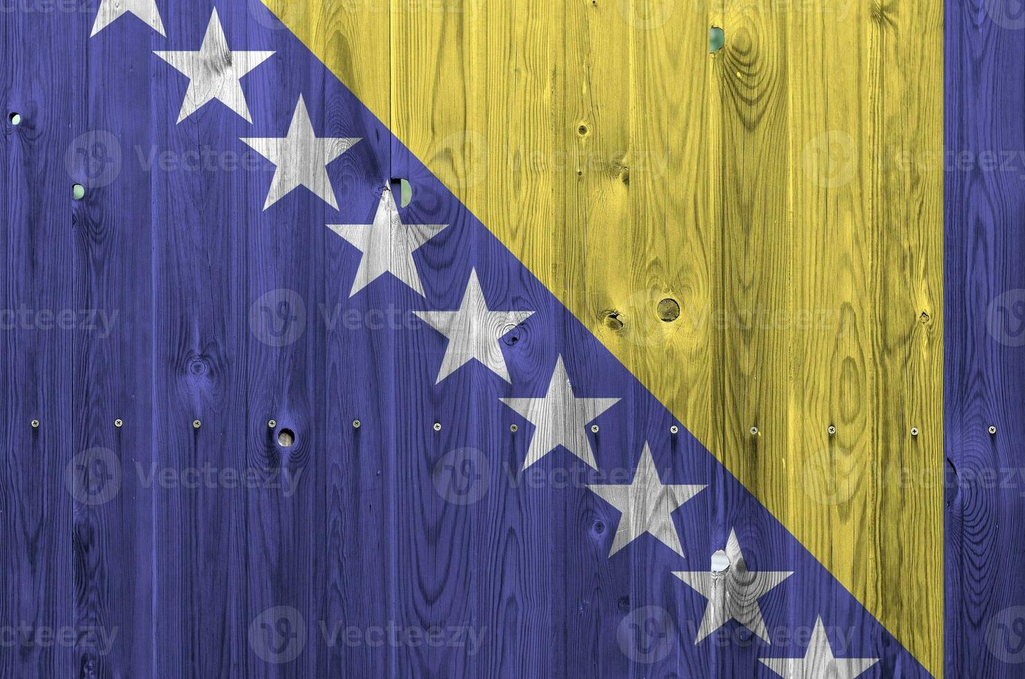 Bosnia and Herzegovina flag depicted in bright paint colors on old wooden wall. Textured banner on rough background photo
