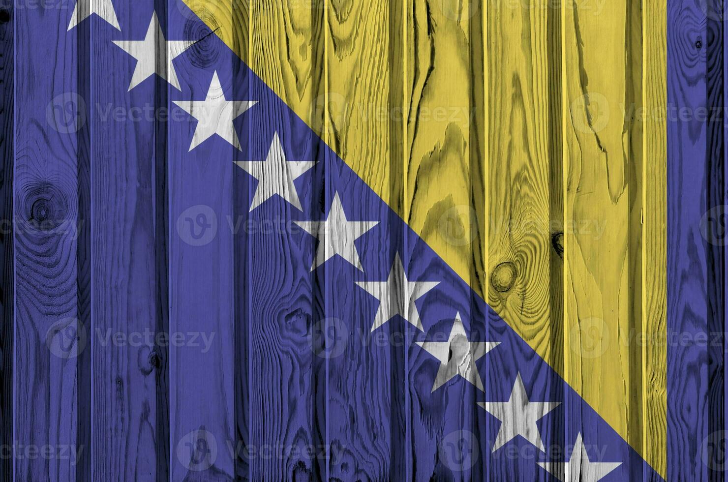 Bosnia and Herzegovina flag depicted in bright paint colors on old wooden wall. Textured banner on rough background photo