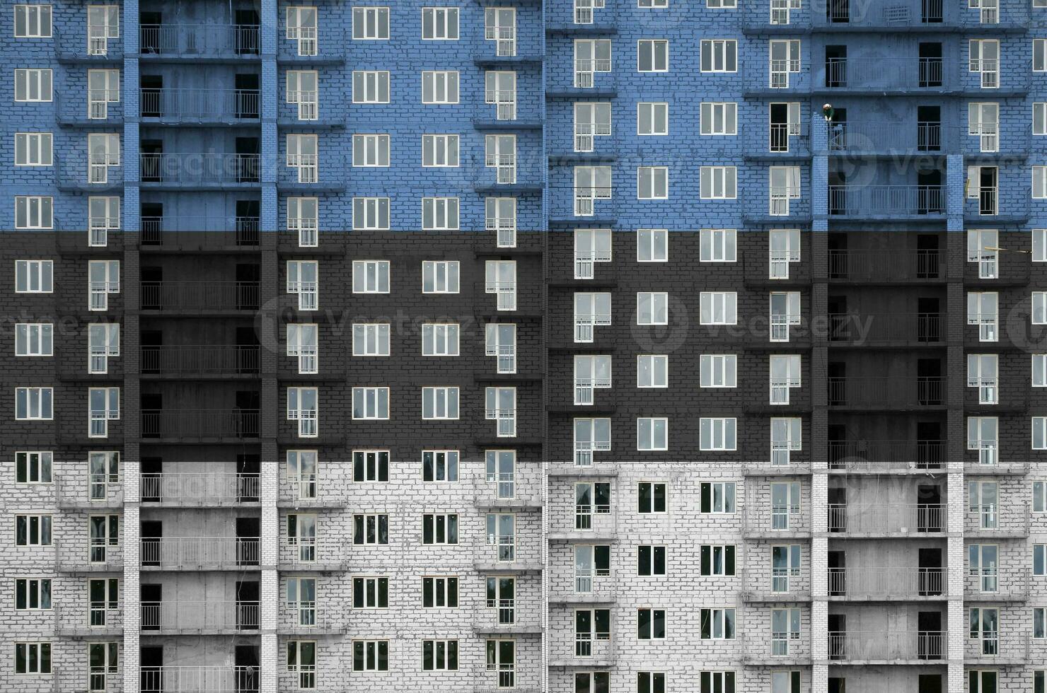 Estonia flag depicted in paint colors on multi-storey residental building under construction. Textured banner on brick wall background photo