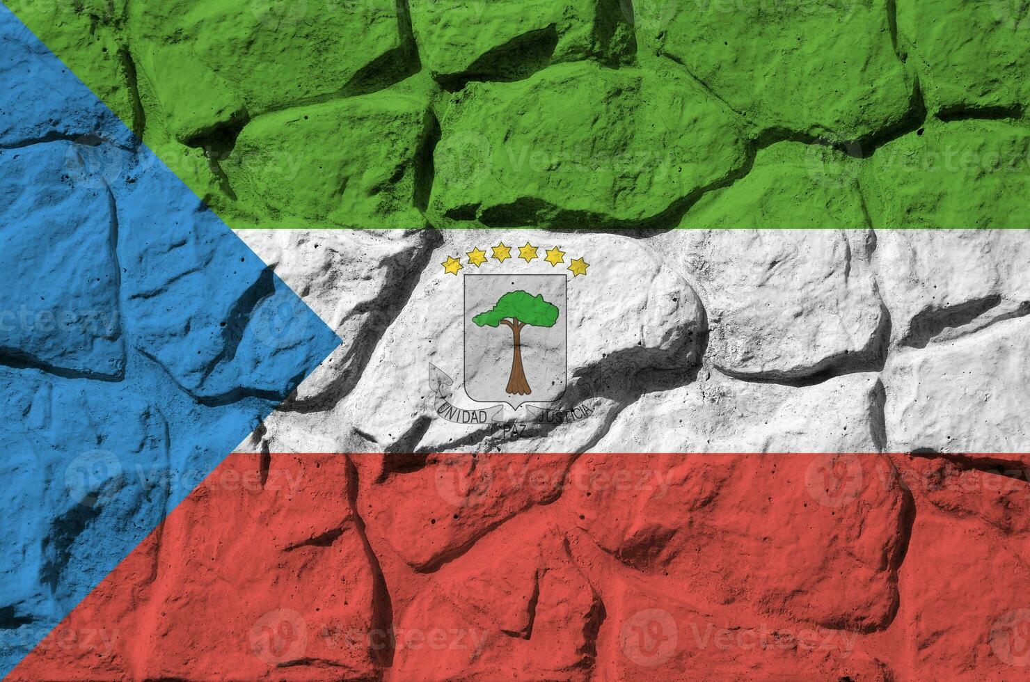 Equatorial Guinea flag depicted in paint colors on old stone wall closeup. Textured banner on rock wall background photo