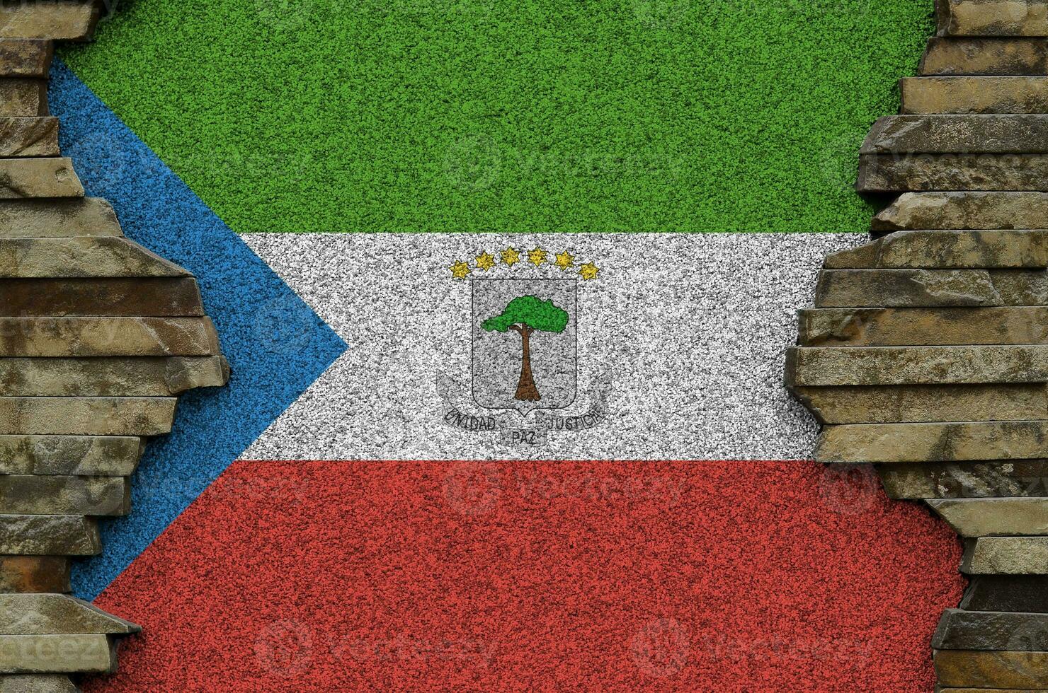 Equatorial Guinea flag depicted in paint colors on old stone wall closeup. Textured banner on rock wall background photo