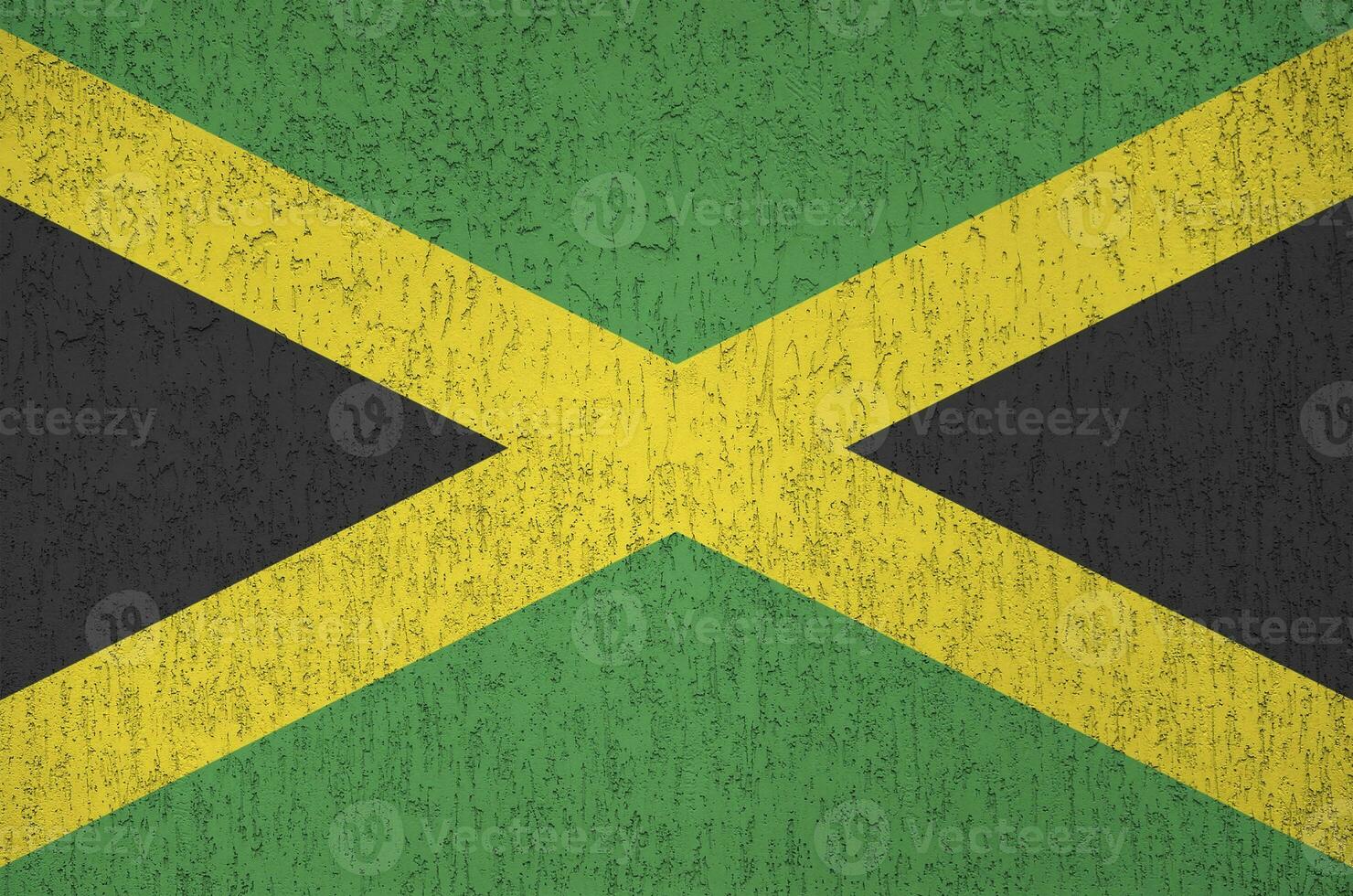 Jamaica flag depicted in bright paint colors on old relief plastering wall. Textured banner on rough background photo