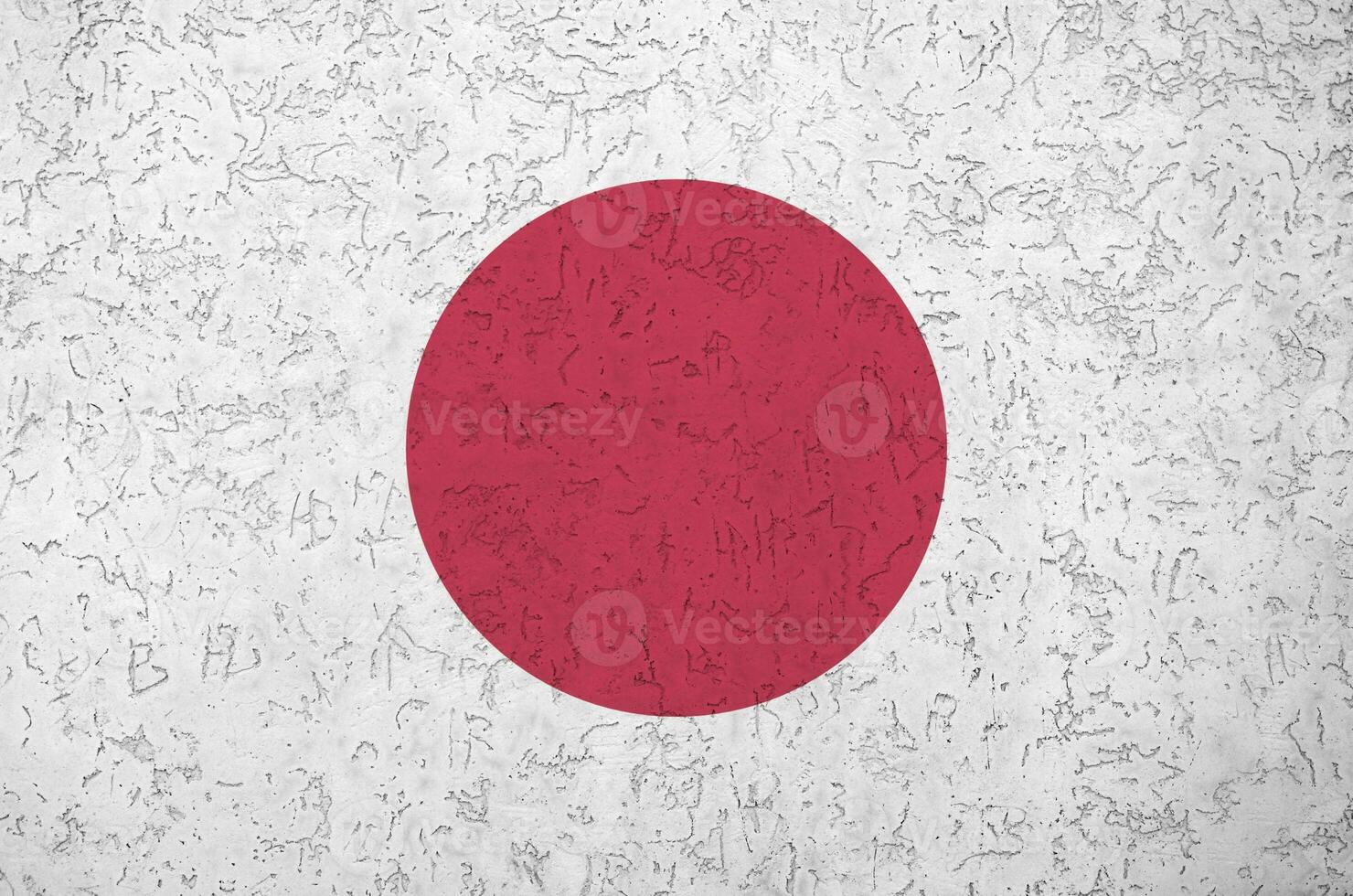 Japan flag depicted in bright paint colors on old relief plastering wall. Textured banner on rough background photo