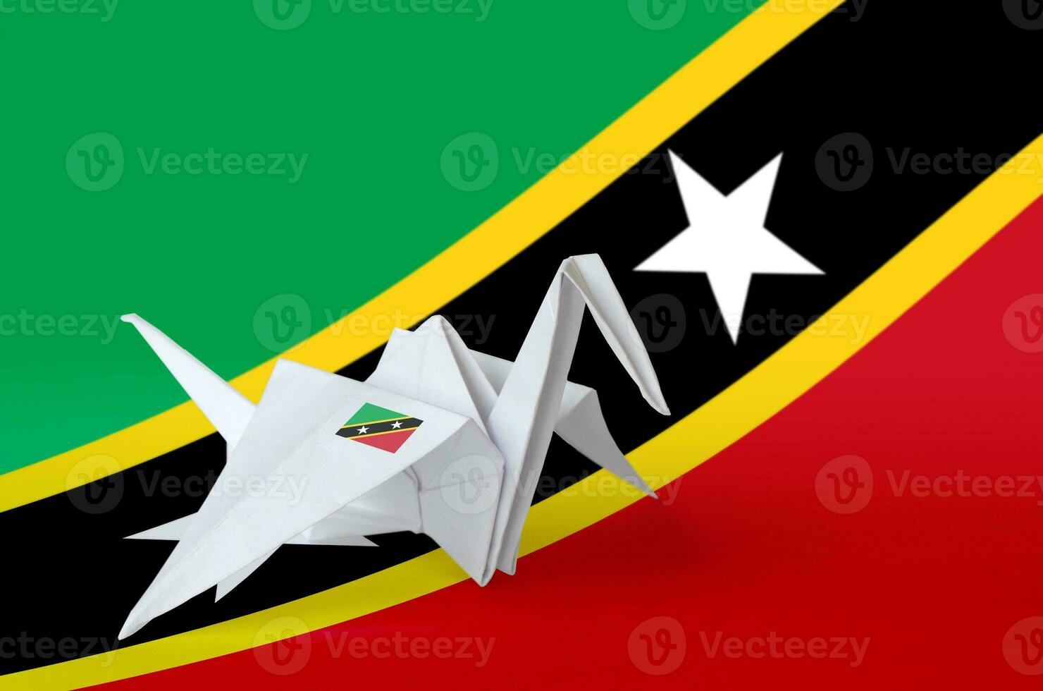 Saint Kitts and Nevis flag depicted on paper origami crane wing. Handmade arts concept photo