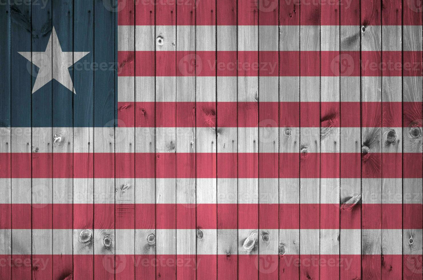 Liberia bandera representado en brillante pintar colores en antiguo de madera pared. texturizado bandera en áspero antecedentes foto