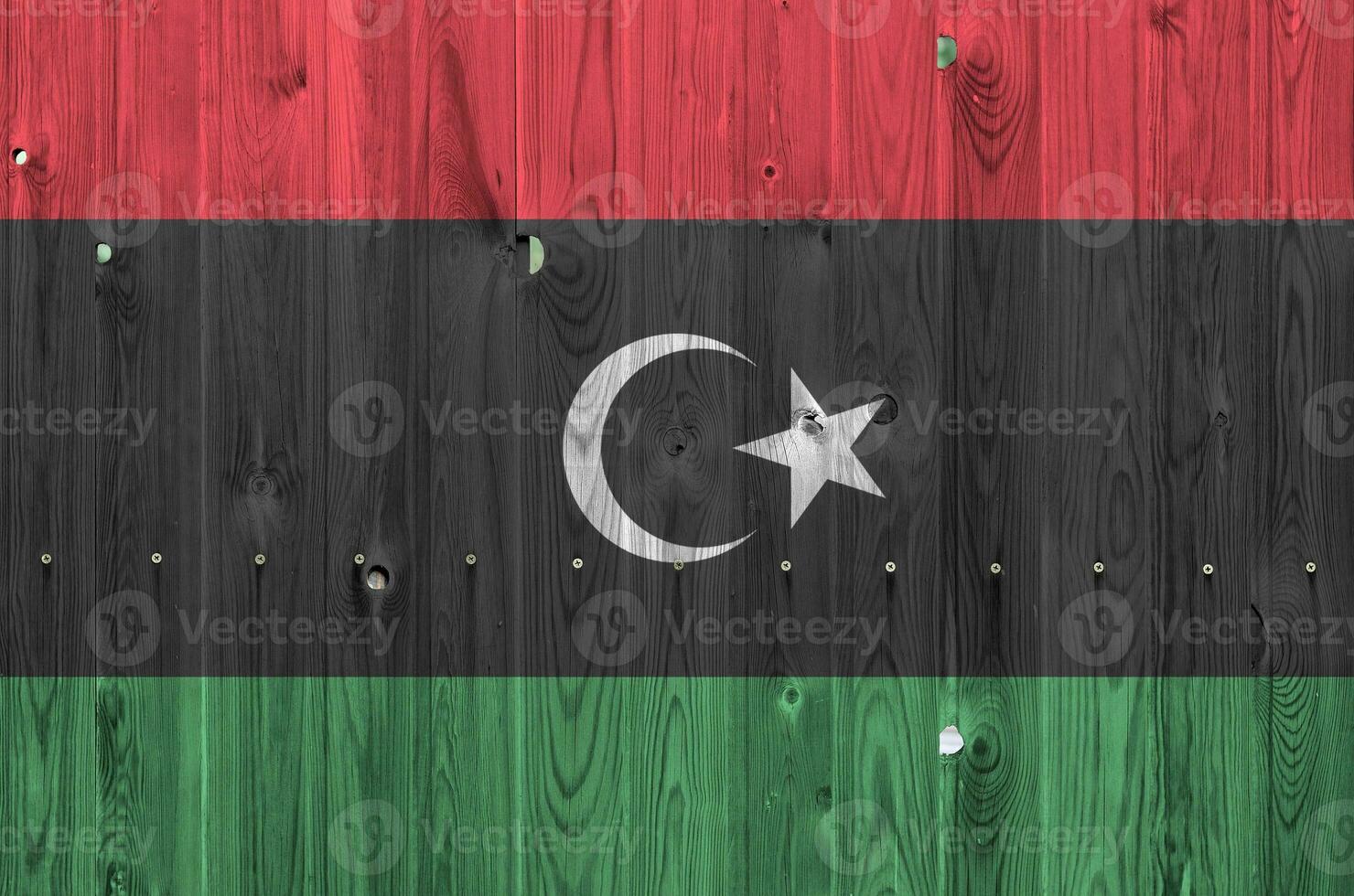 Libya flag depicted in bright paint colors on old wooden wall. Textured banner on rough background photo