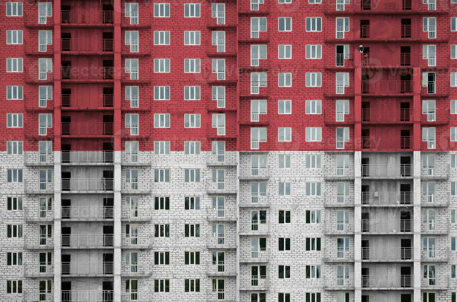 Monaco flag depicted in paint colors on multi-storey residental building under construction. Textured banner on brick wall background photo