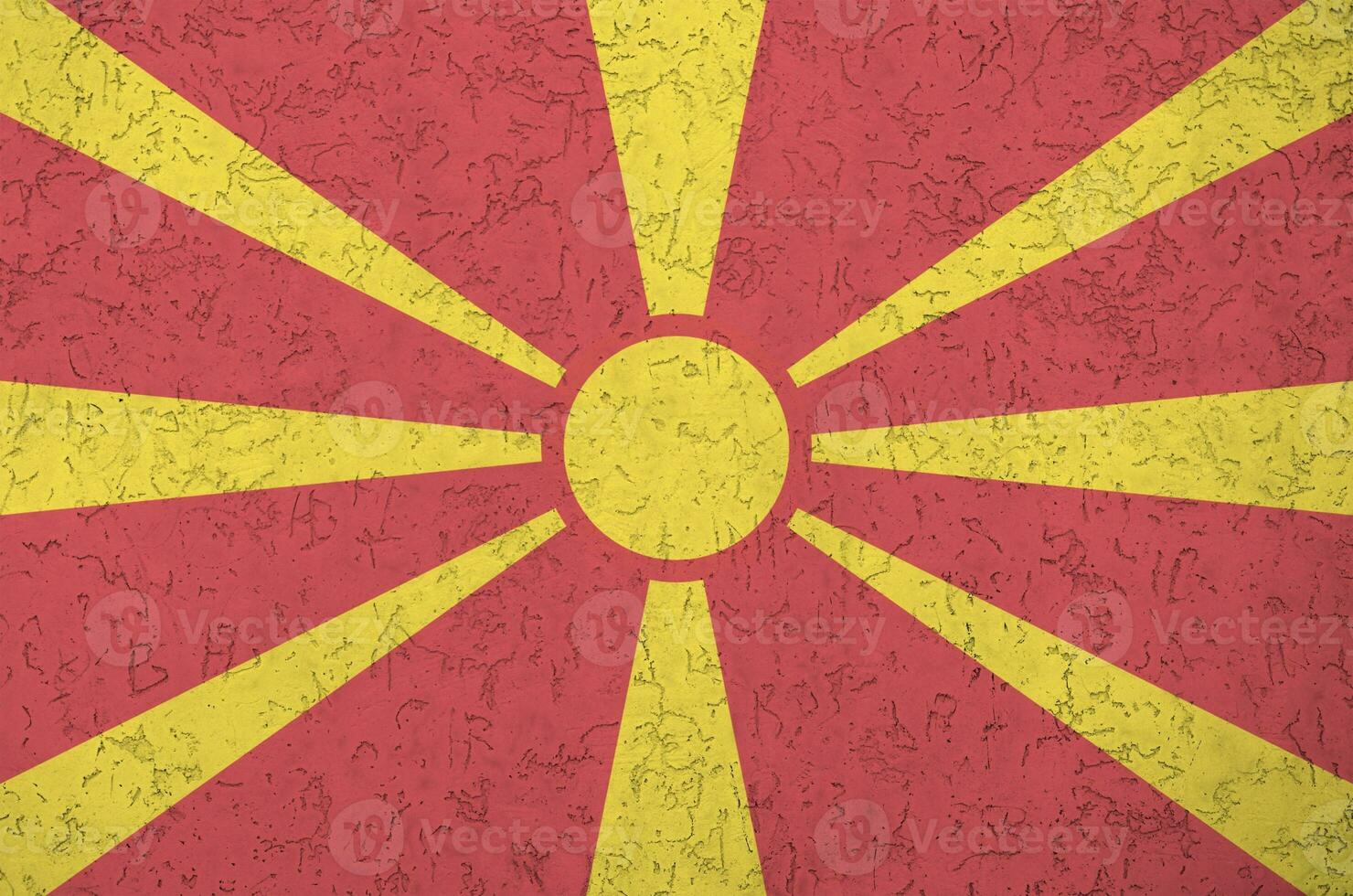 Macedonia flag depicted in bright paint colors on old relief plastering wall. Textured banner on rough background photo