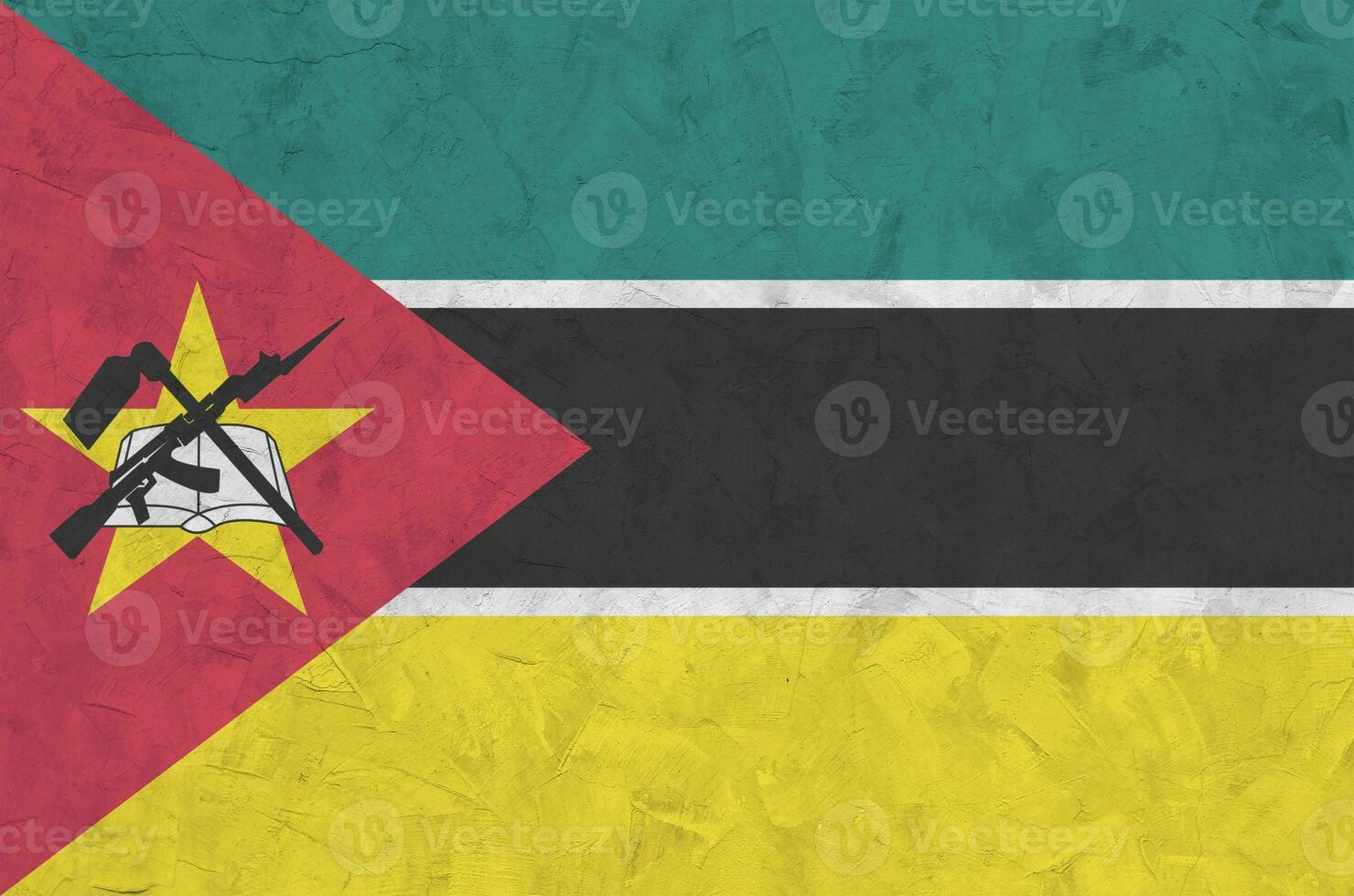 Mozambique flag depicted in bright paint colors on old relief plastering wall. Textured banner on rough background photo