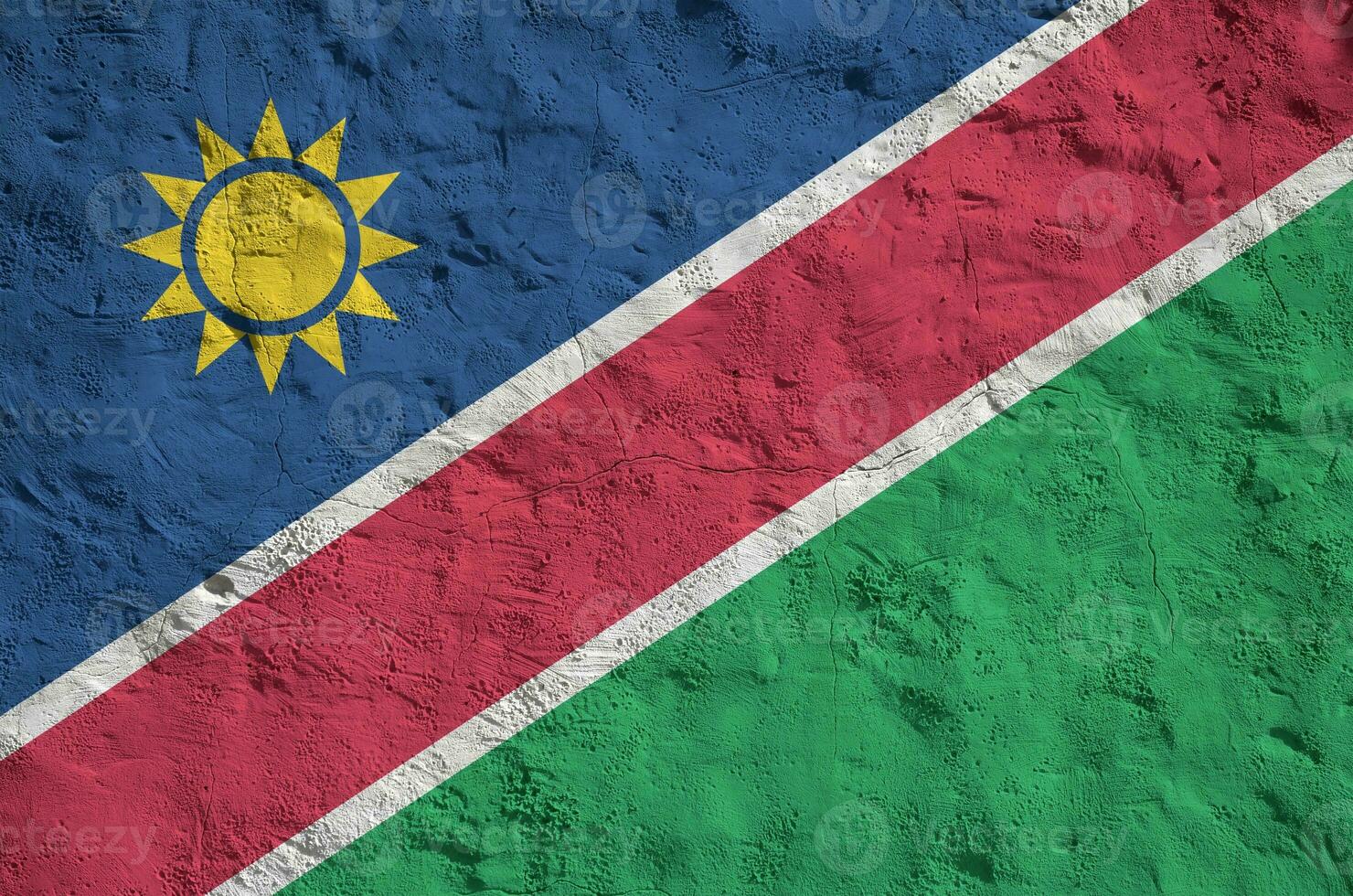 Namibia flag depicted in bright paint colors on old relief plastering wall. Textured banner on rough background photo