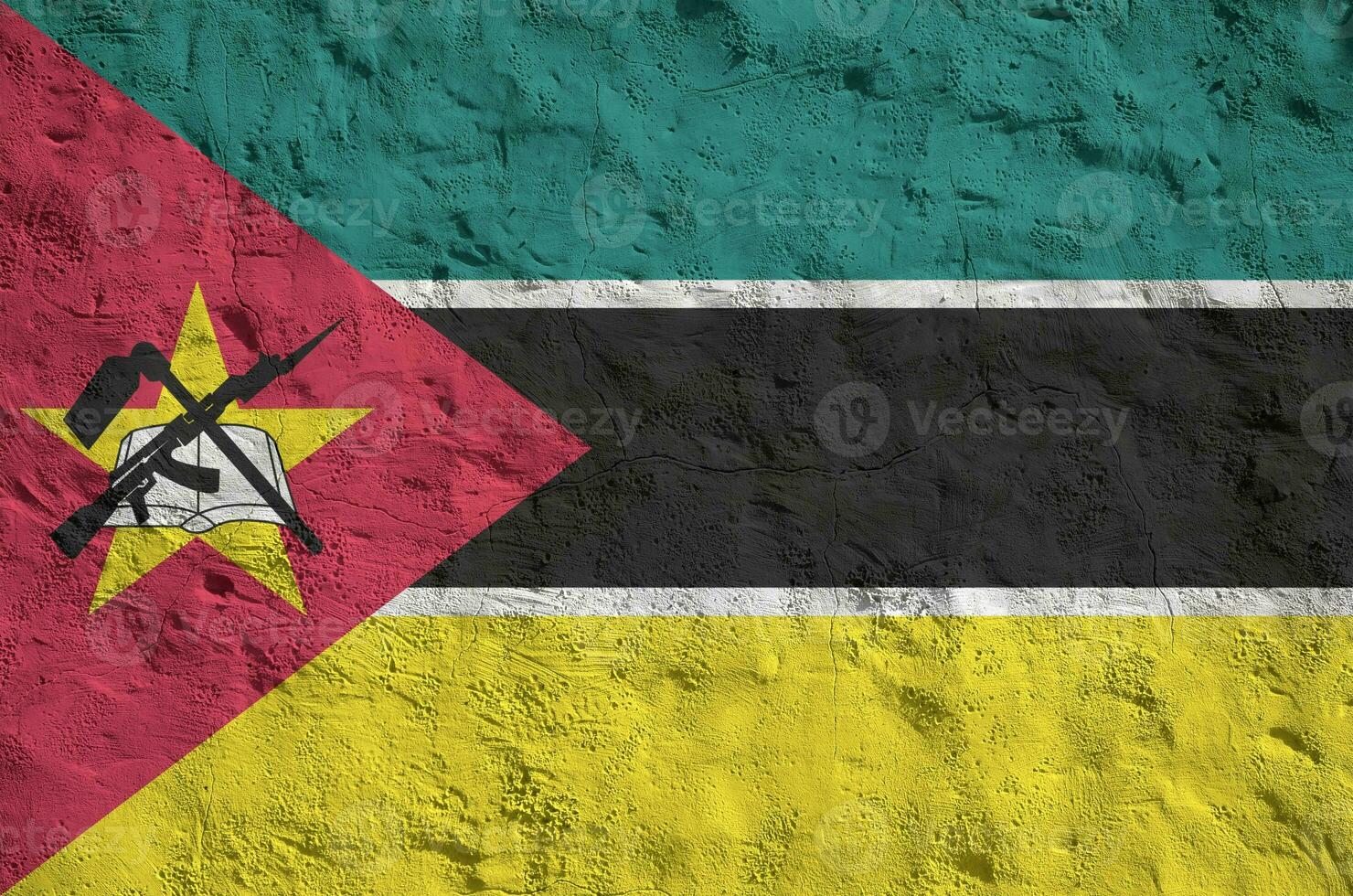 Mozambique flag depicted in bright paint colors on old relief plastering wall. Textured banner on rough background photo