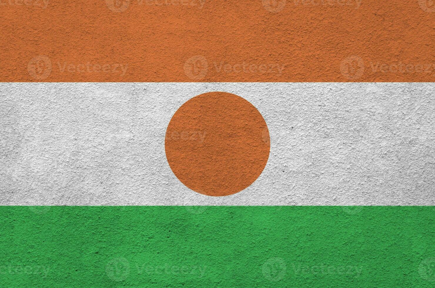 Niger flag depicted in bright paint colors on old relief plastering wall. Textured banner on rough background photo