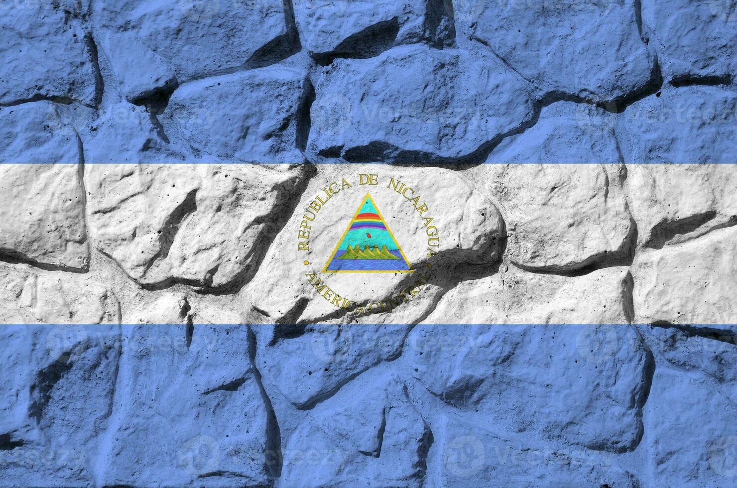 Nicaragua flag depicted in paint colors on old stone wall closeup. Textured banner on rock wall background photo