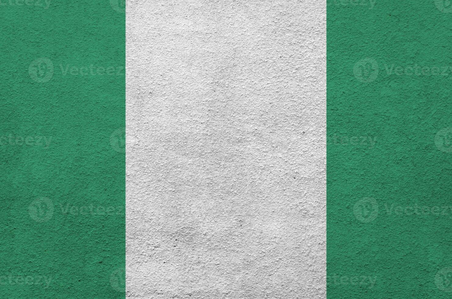 Nigeria flag depicted in bright paint colors on old relief plastering wall. Textured banner on rough background photo