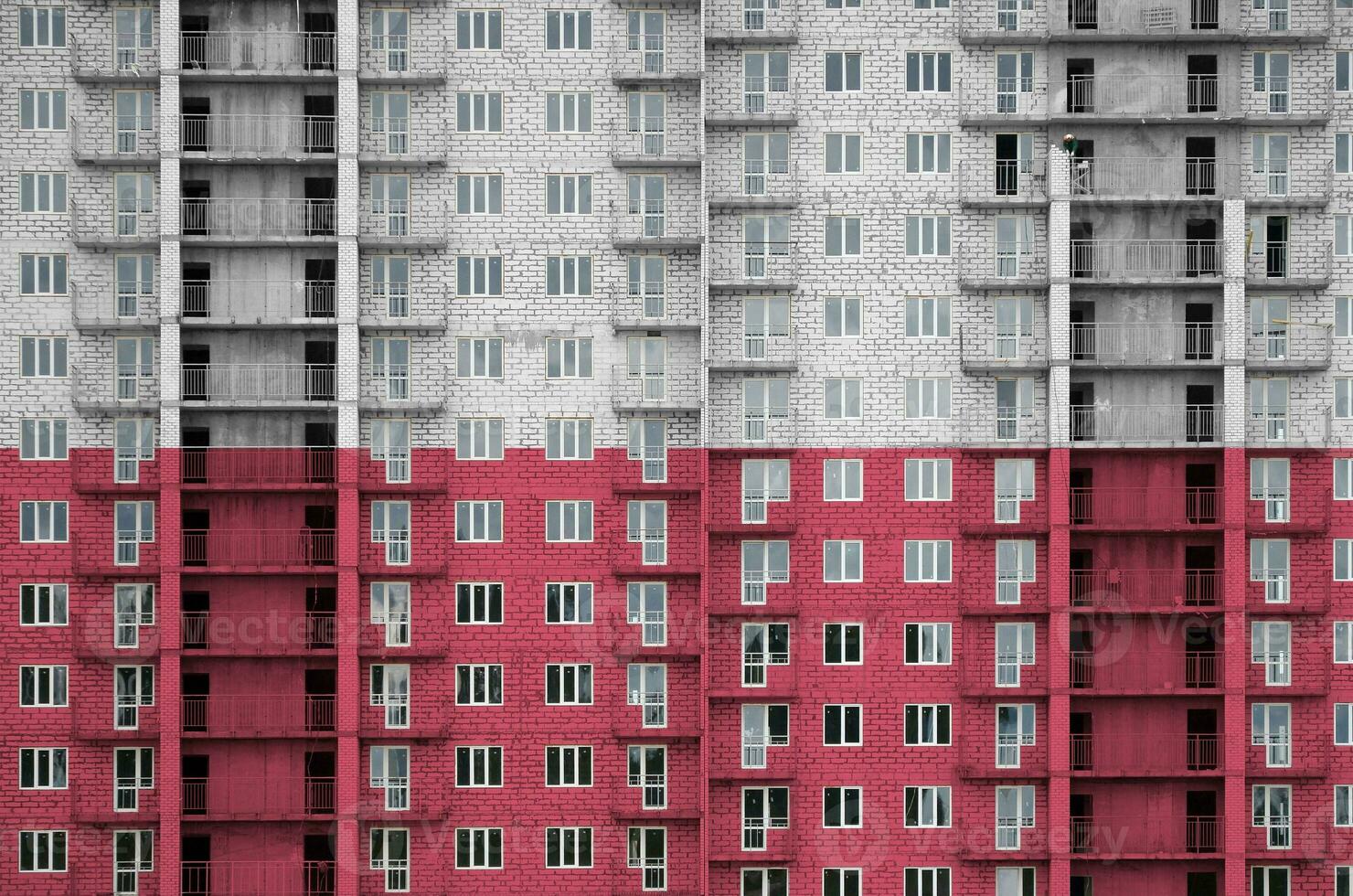 Poland flag depicted in paint colors on multi-storey residental building under construction. Textured banner on brick wall background photo