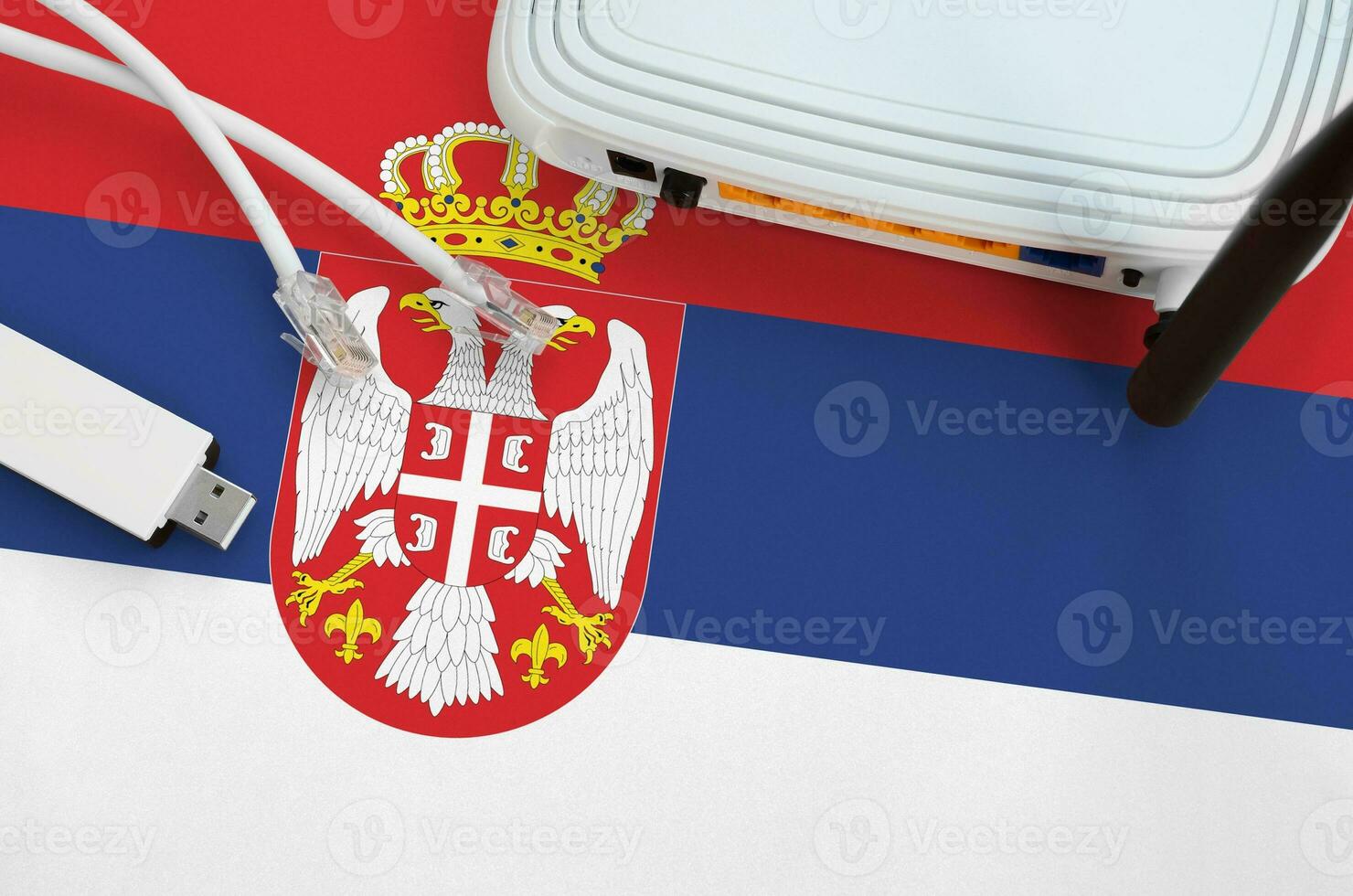 Serbia flag depicted on table with internet rj45 cable, wireless usb wifi adapter and router. Internet connection concept photo