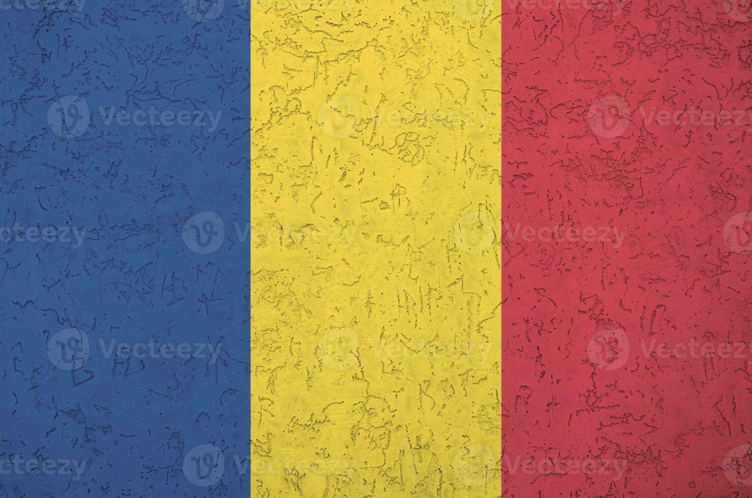 Romania flag depicted in bright paint colors on old relief plastering wall. Textured banner on rough background photo