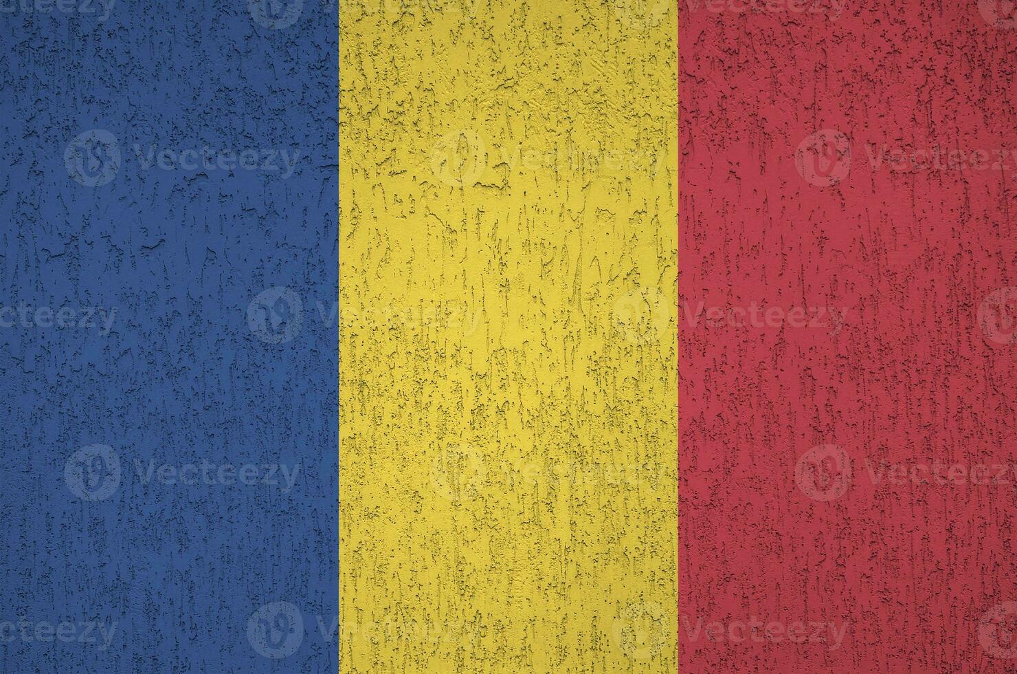 Romania flag depicted in bright paint colors on old relief plastering wall. Textured banner on rough background photo