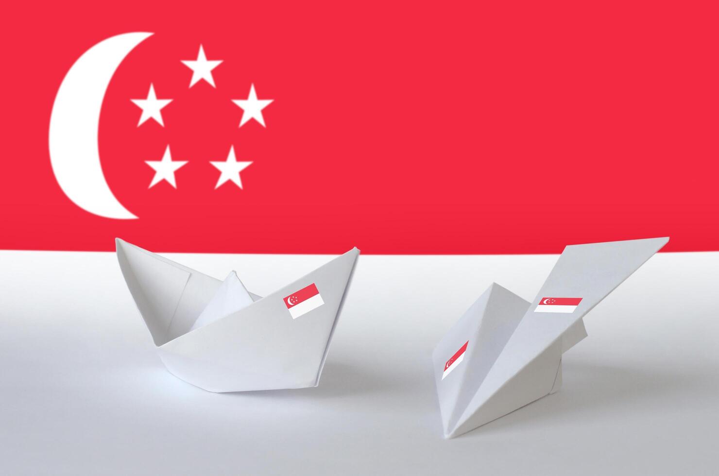 Singapore flag depicted on paper origami airplane and boat. Handmade arts concept photo