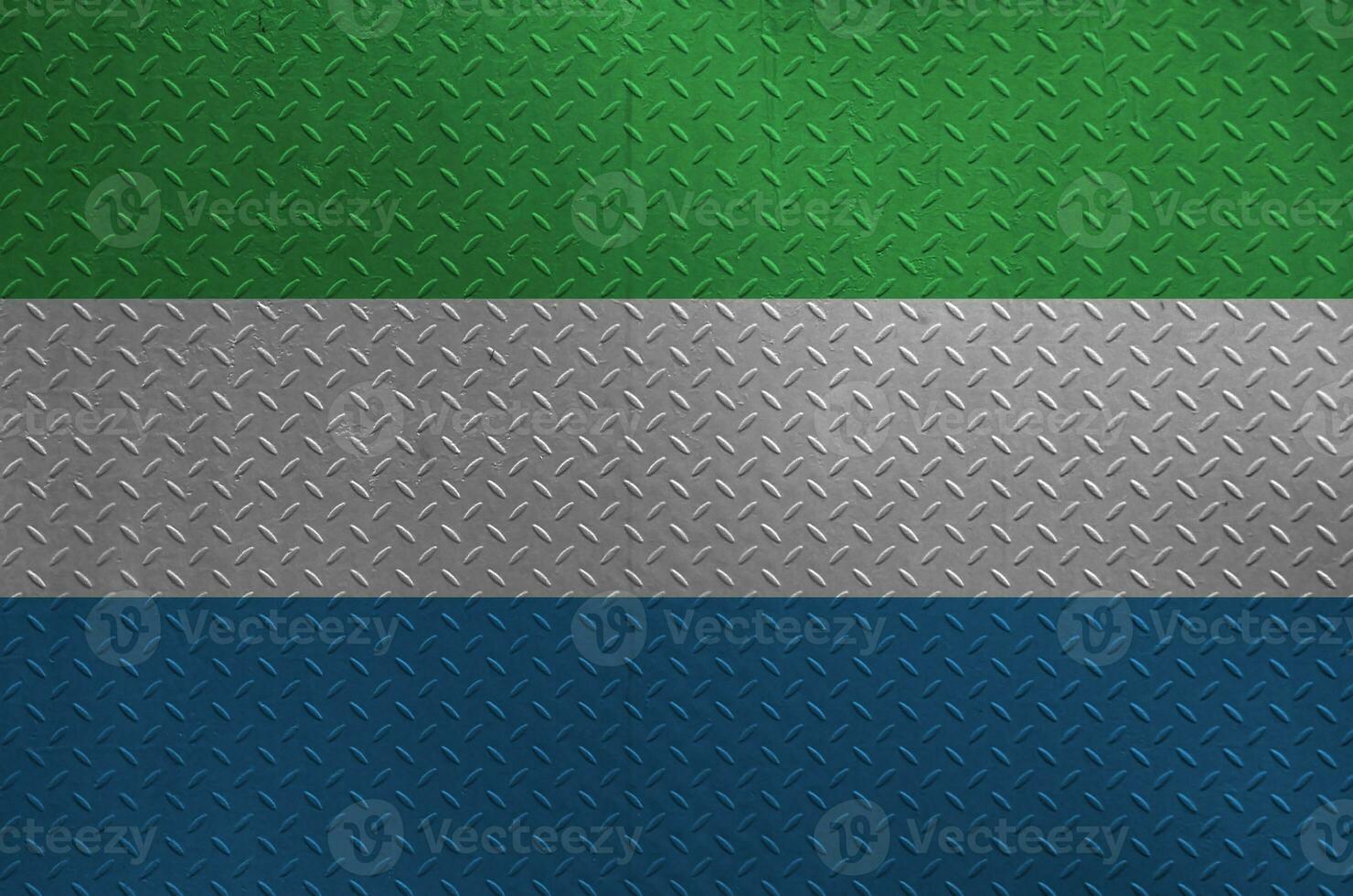 Sierra Leone flag depicted in paint colors on old brushed metal plate or wall closeup. Textured banner on rough background photo