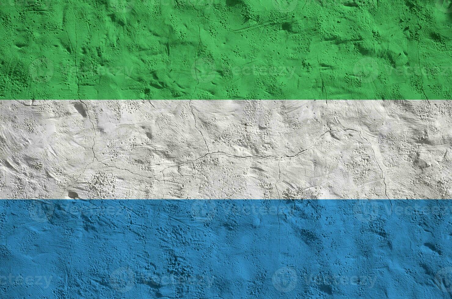 Sierra Leone flag depicted in bright paint colors on old relief plastering wall. Textured banner on rough background photo