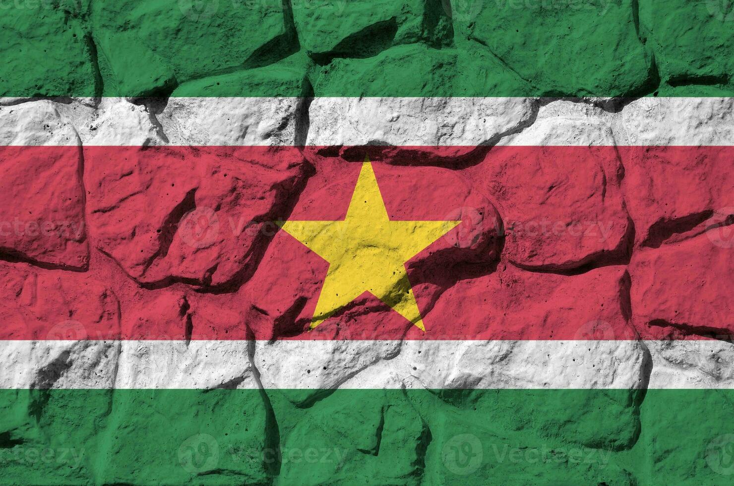 Suriname flag depicted in paint colors on old stone wall closeup. Textured banner on rock wall background photo