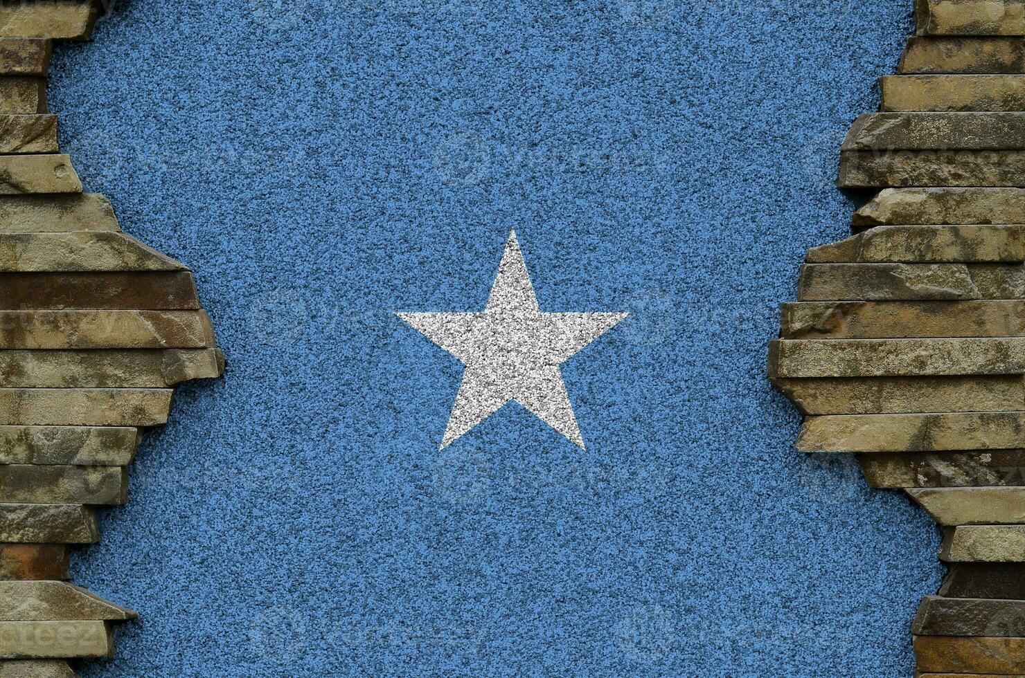 Somalia flag depicted in paint colors on old stone wall closeup. Textured banner on rock wall background photo