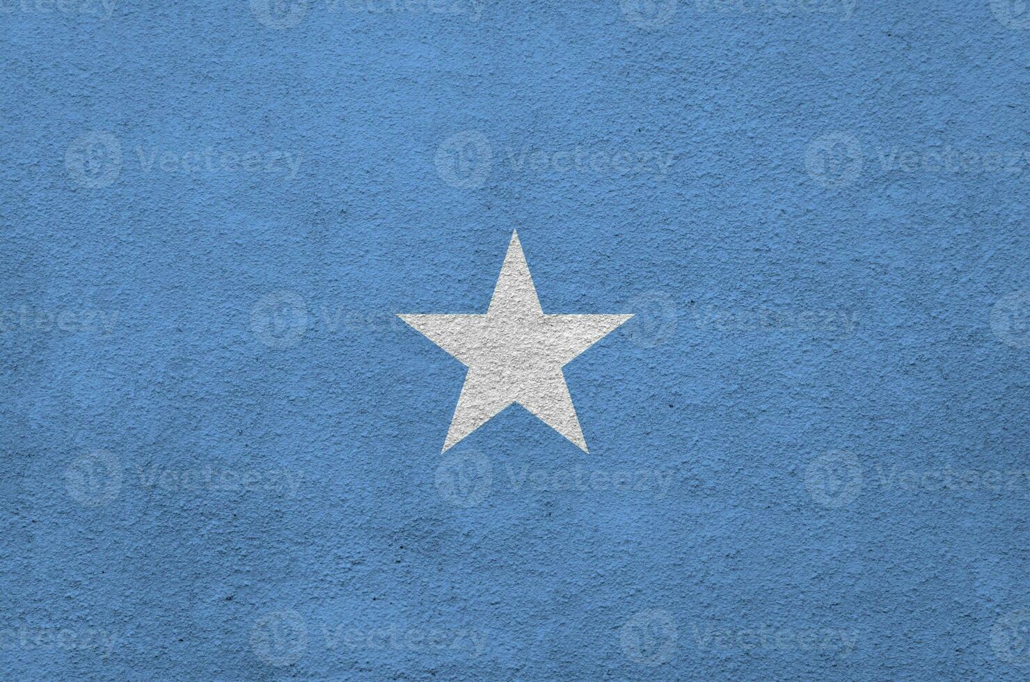 Somalia flag depicted in bright paint colors on old relief plastering wall. Textured banner on rough background photo