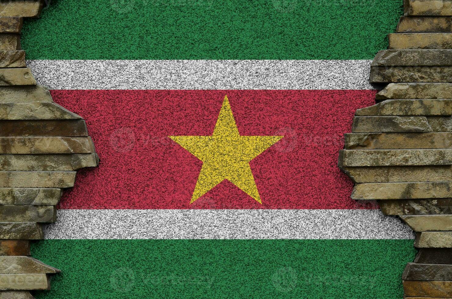 Suriname flag depicted in paint colors on old stone wall closeup. Textured banner on rock wall background photo