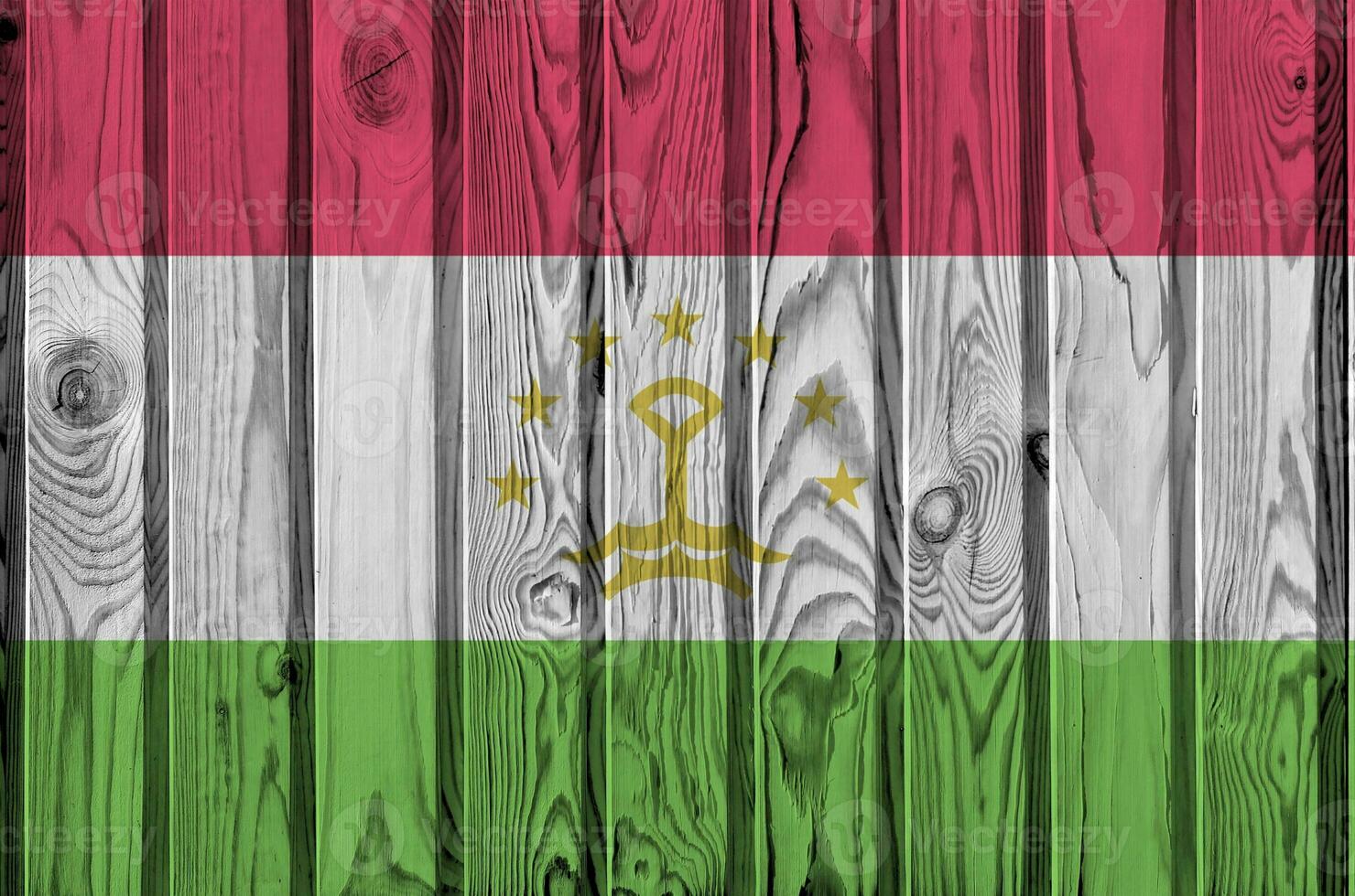 Tajikistan flag depicted in bright paint colors on old wooden wall. Textured banner on rough background photo