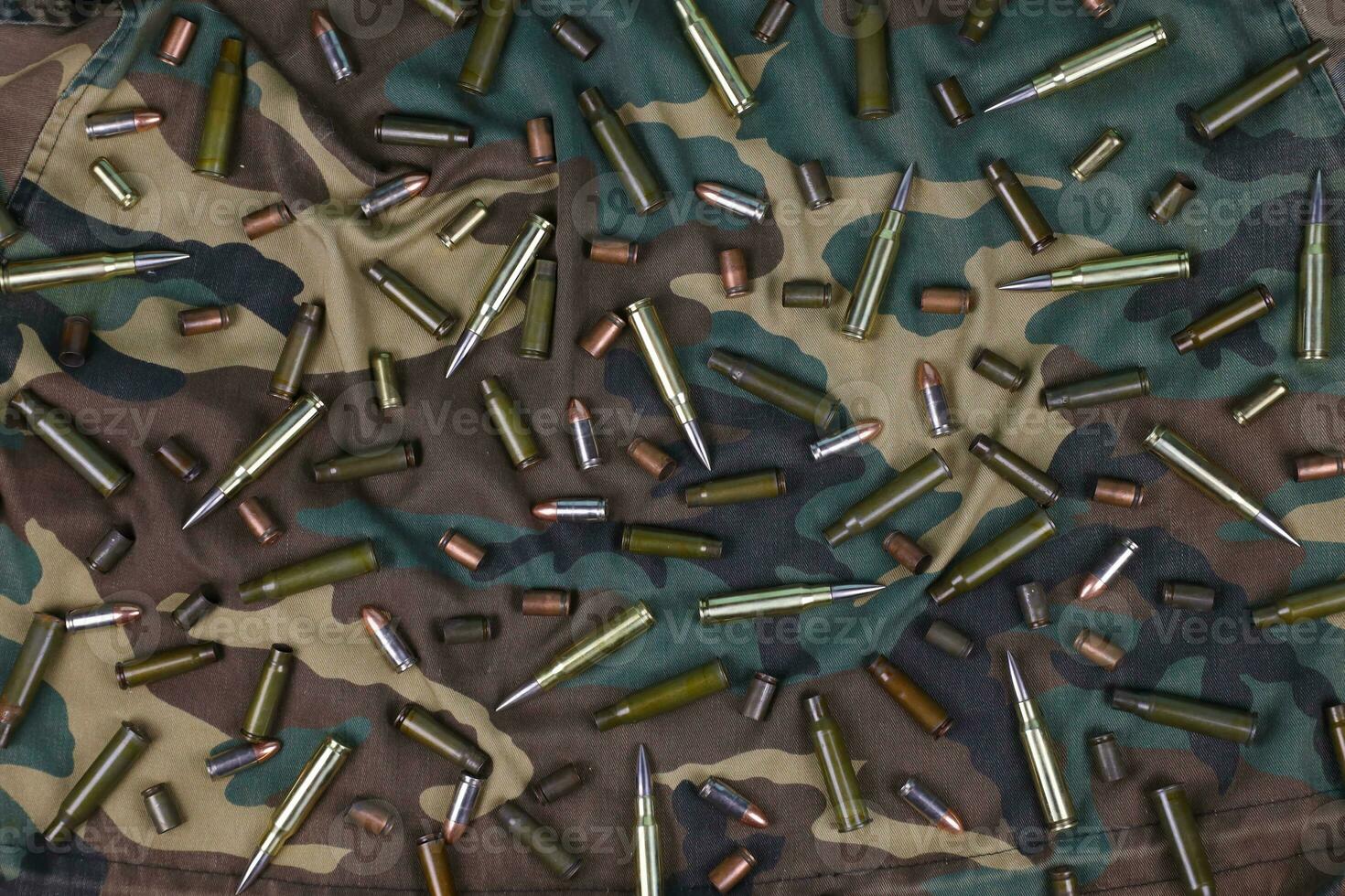 Many rifle bullets and cartridges on dark camouflage background photo