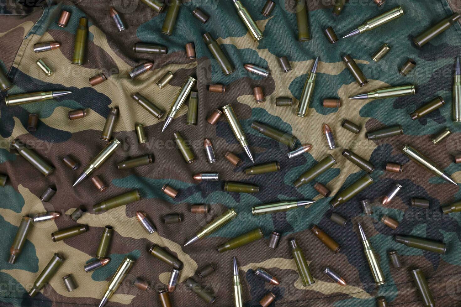 Many rifle bullets and cartridges on dark camouflage background photo