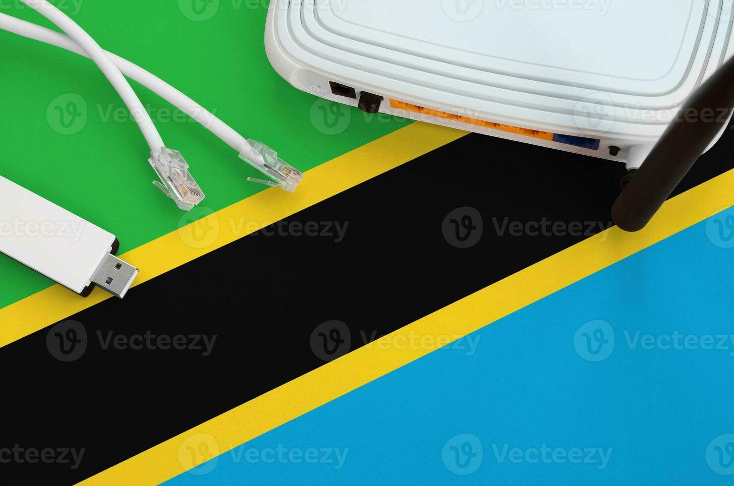 Tanzania flag depicted on table with internet rj45 cable, wireless usb wifi adapter and router. Internet connection concept photo