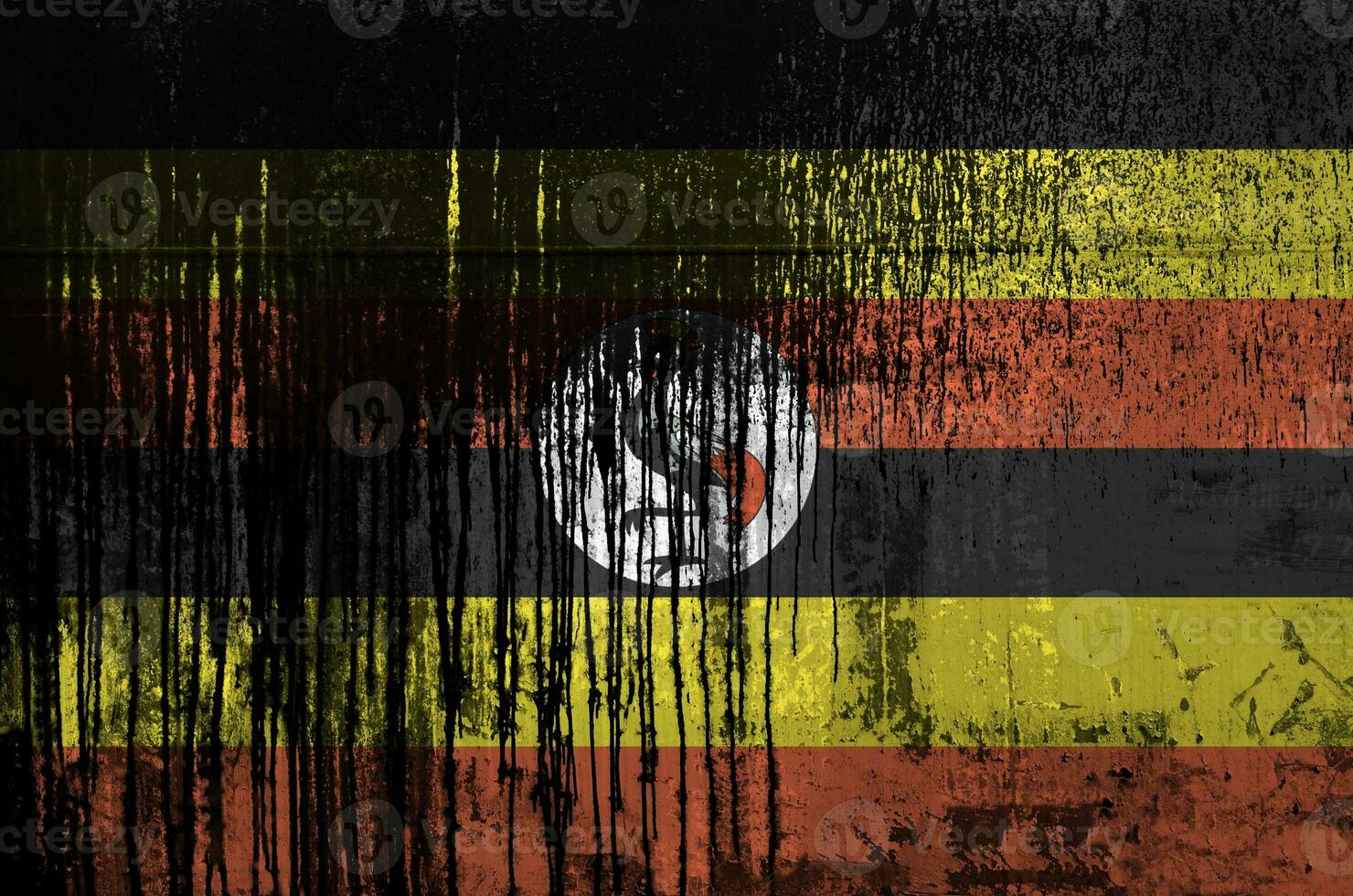 Uganda flag depicted in paint colors on old and dirty oil barrel wall closeup. Textured banner on rough background photo