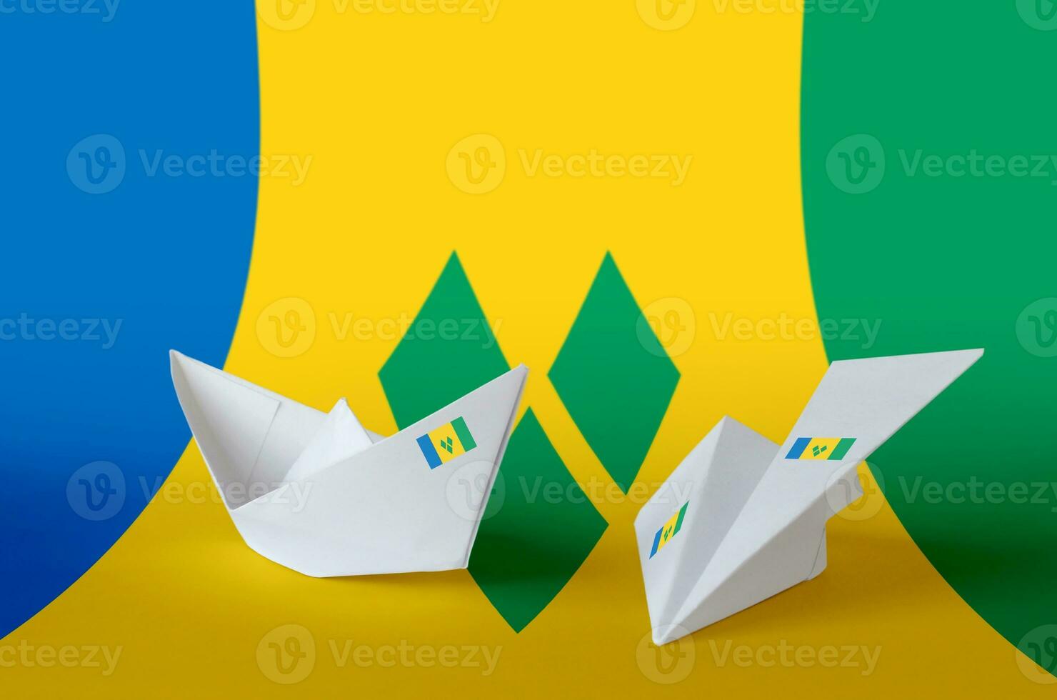 Saint Vincent and the Grenadines flag depicted on paper origami airplane and boat. Handmade arts concept photo