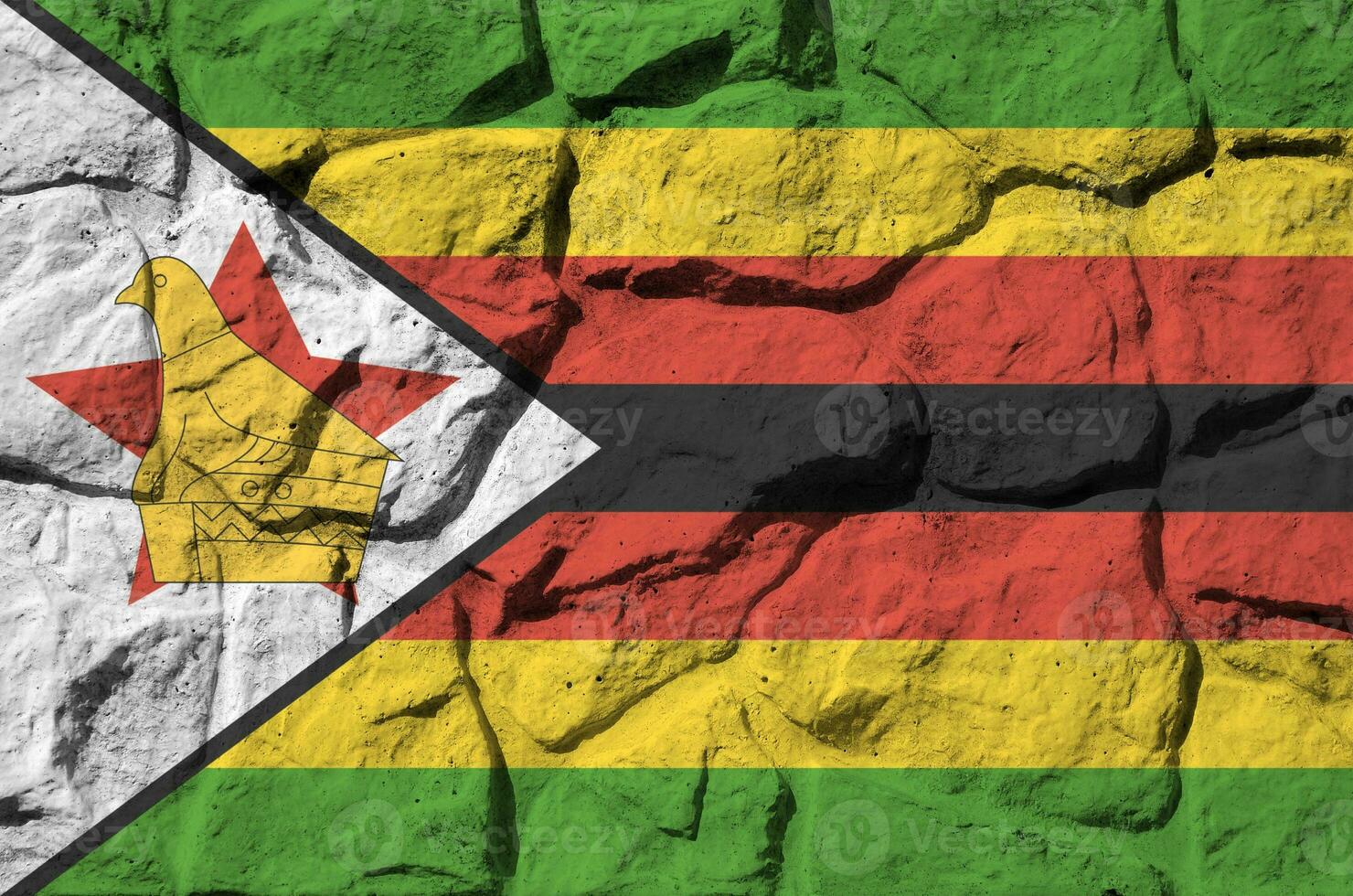 Zimbabwe flag depicted in paint colors on old stone wall closeup. Textured banner on rock wall background photo